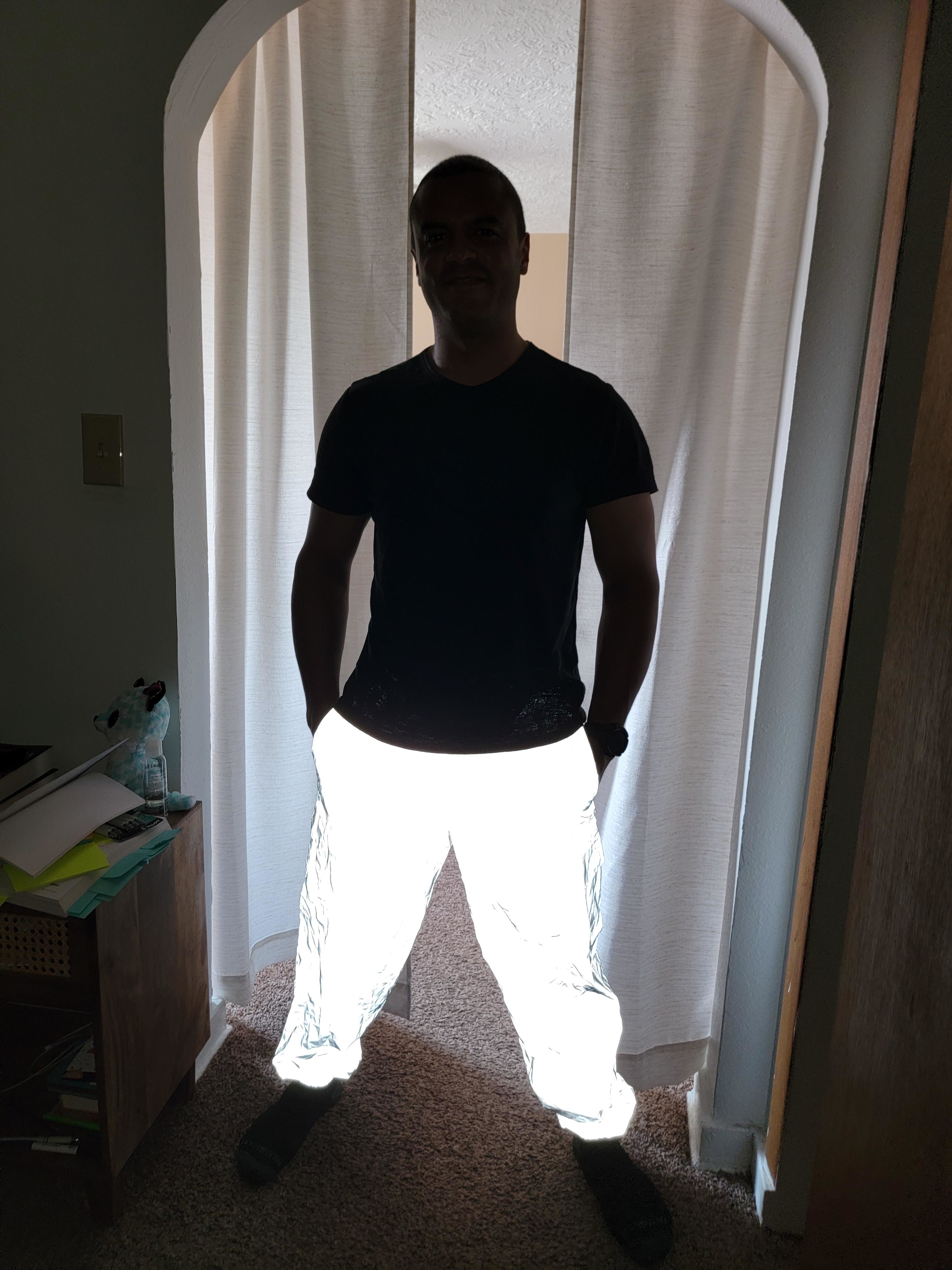 A man in shadows wearing luminous pants