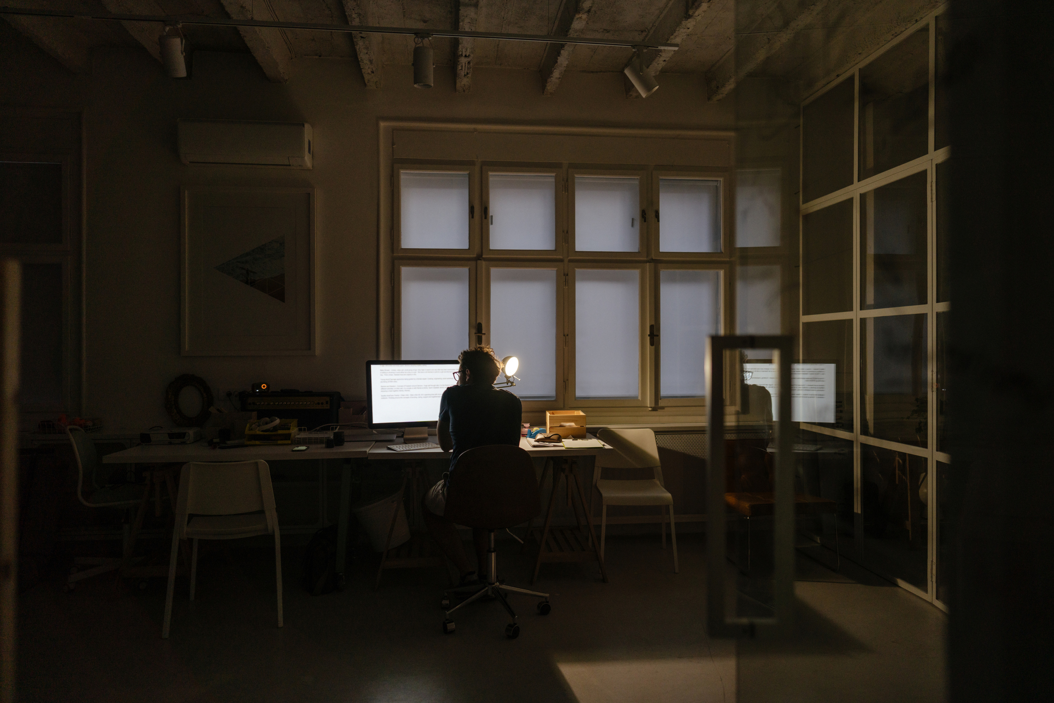 Photo of a man sitting at a desktop computer and working during a late-night shift
