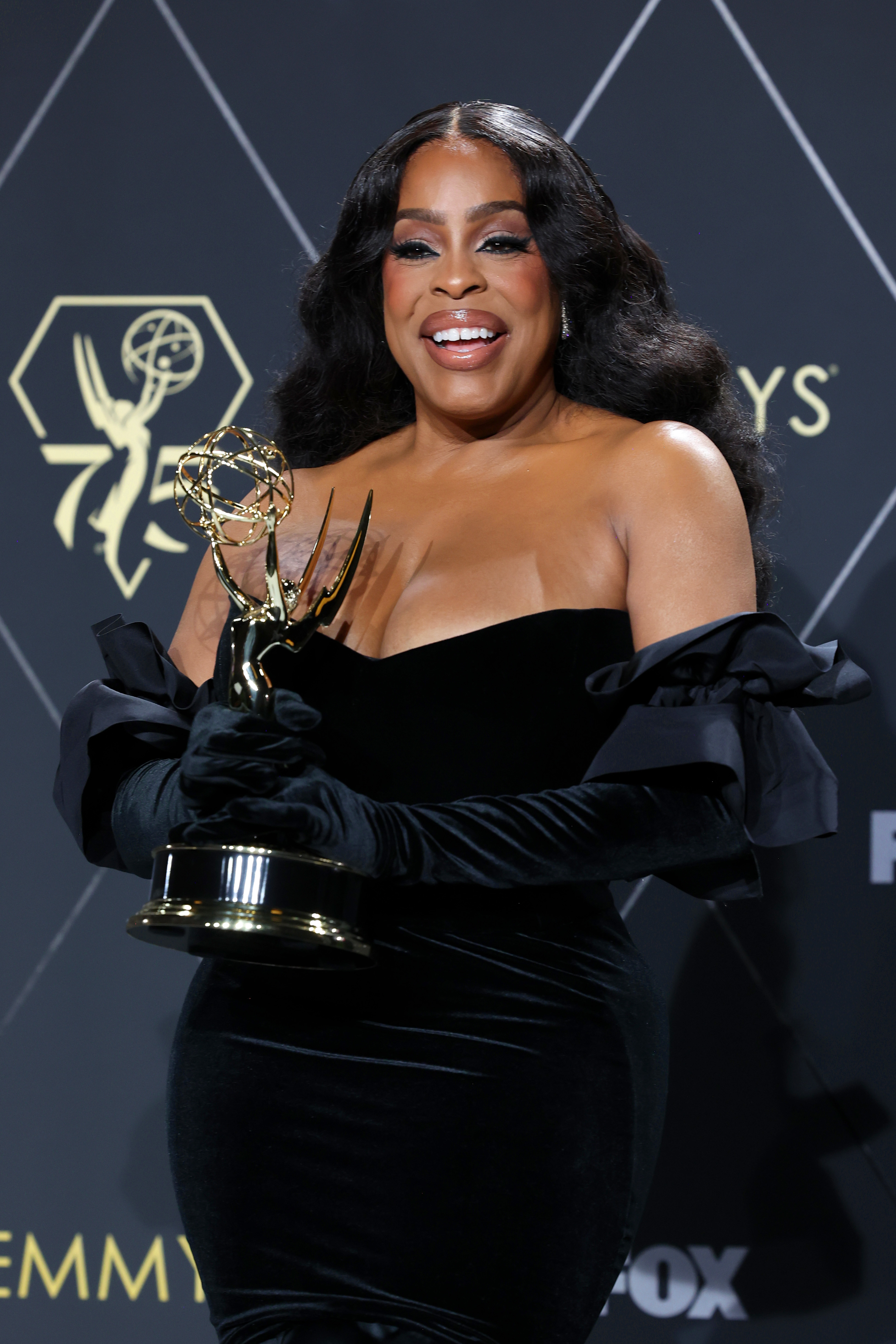 A closeup of Niecy Nash holding her Emmy award backstage