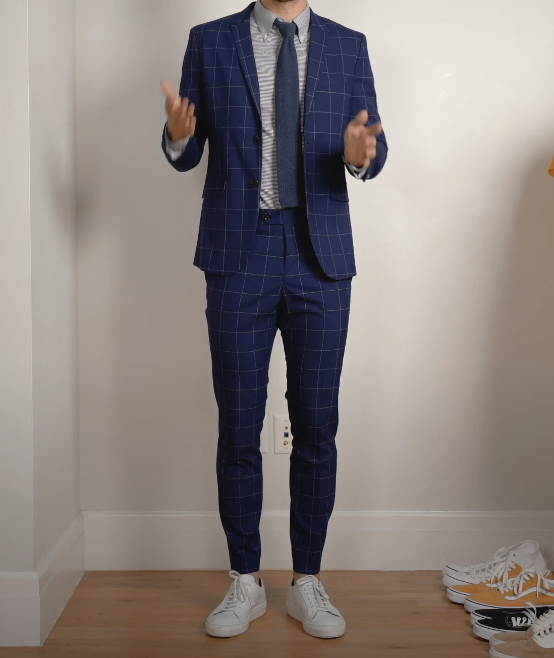 A person wearing a suit and tie with sneakers, no socks