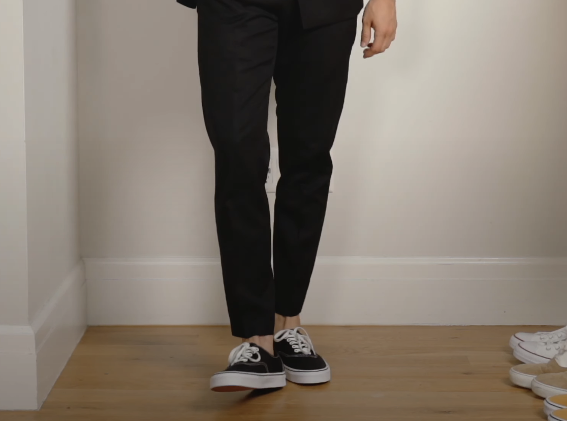 Close-up of someone wearing ankle-length straight pants, no socks, and sneakers