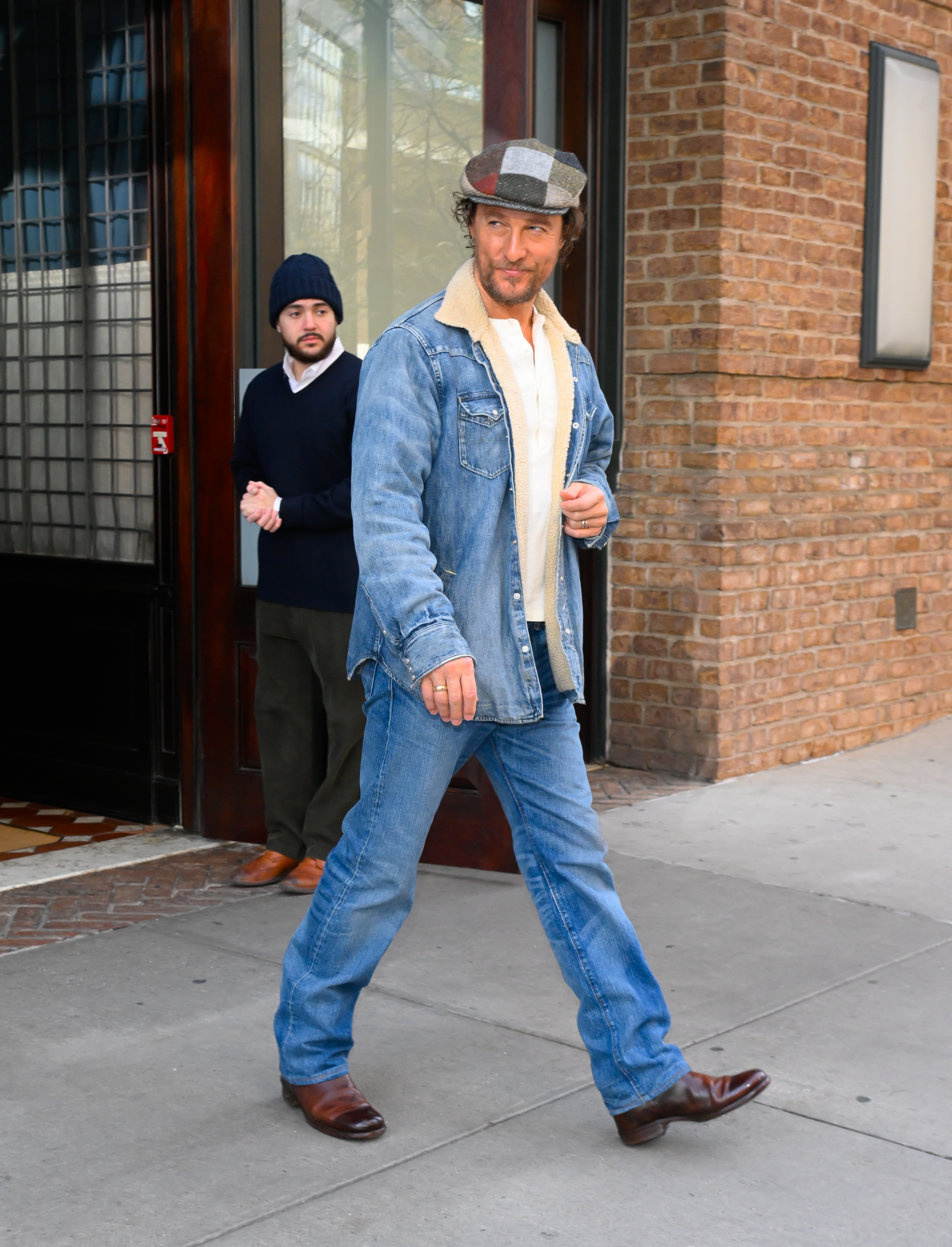 Close-up of Matthew on the street in a cap, denim jacket, and jeans