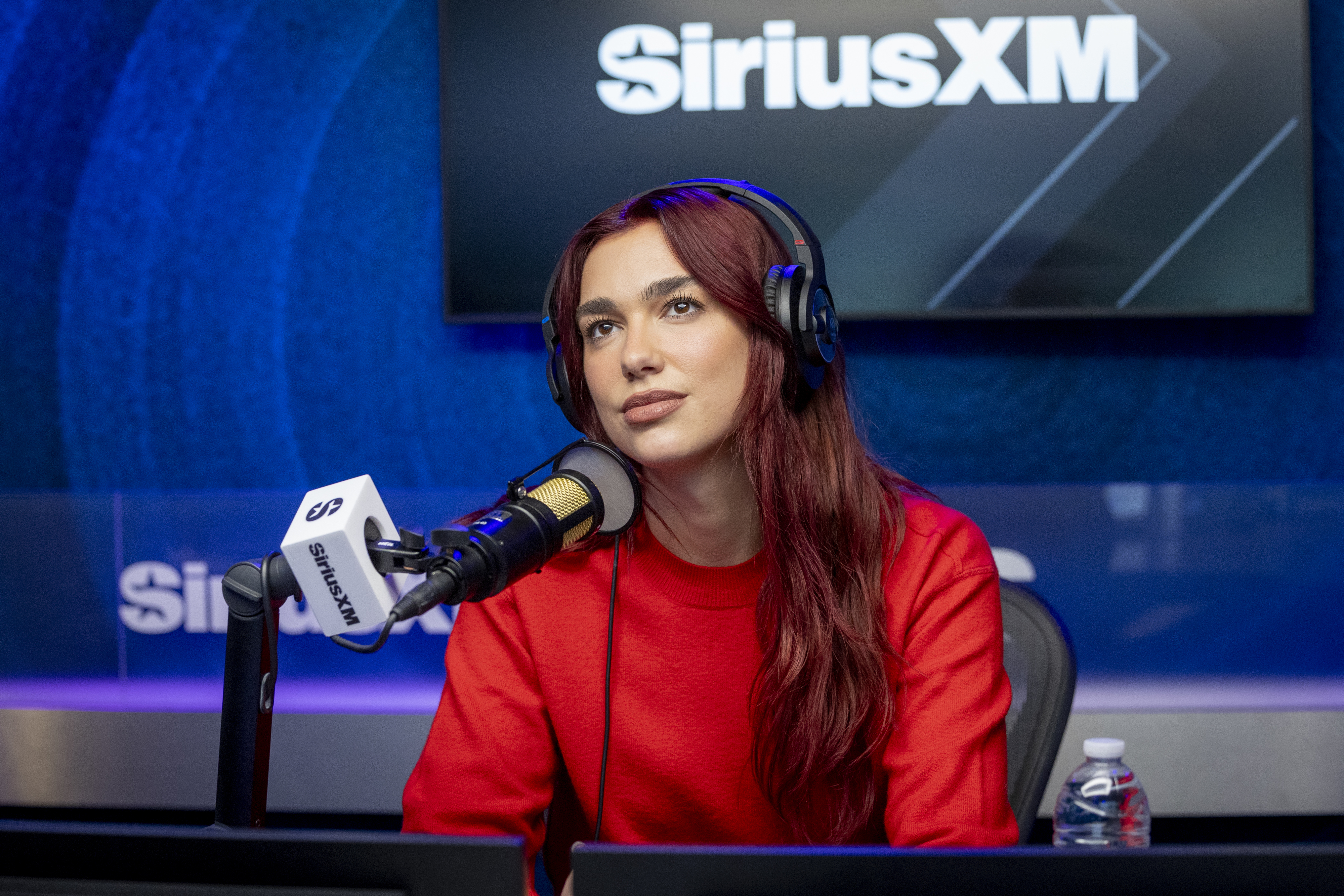 A closeup of Dua in front of a mic during a sirius xm interview