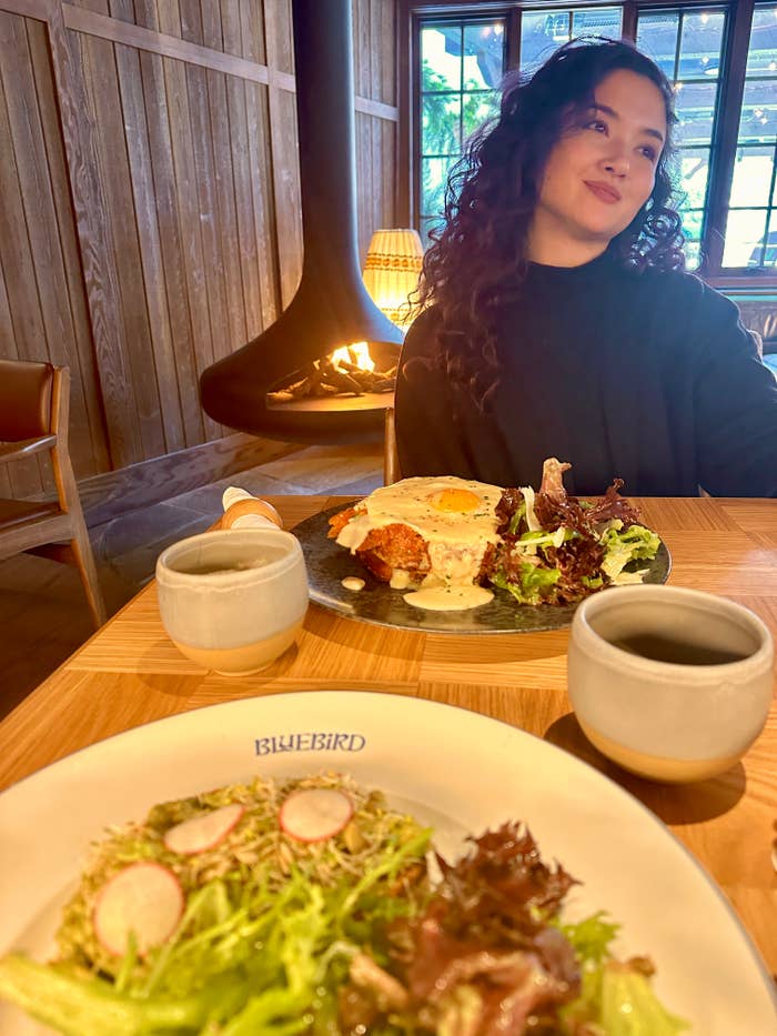 Two plates of brunch, with a fireplace and girl in the background.