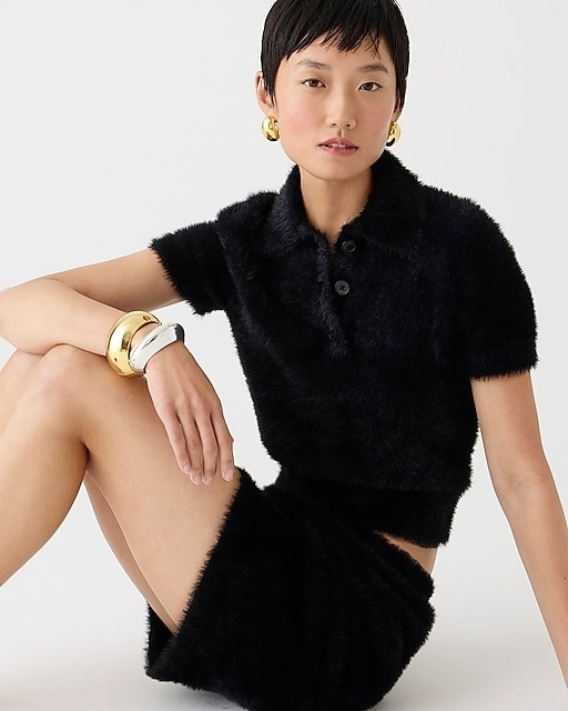 model in black short sleeve fuzzy polo and mini skirt set
