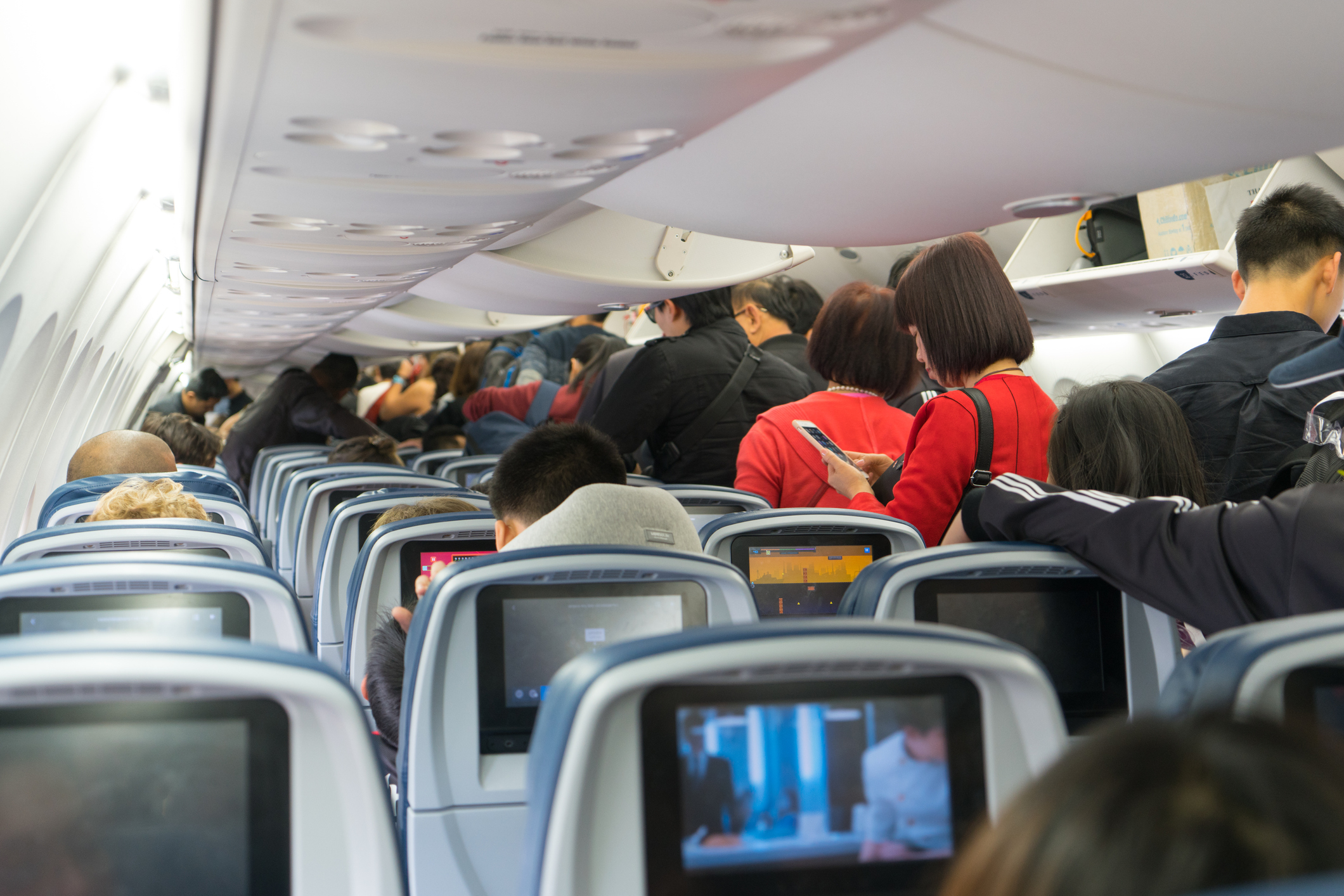 People standing in an airplane aisle cabin before disembarking