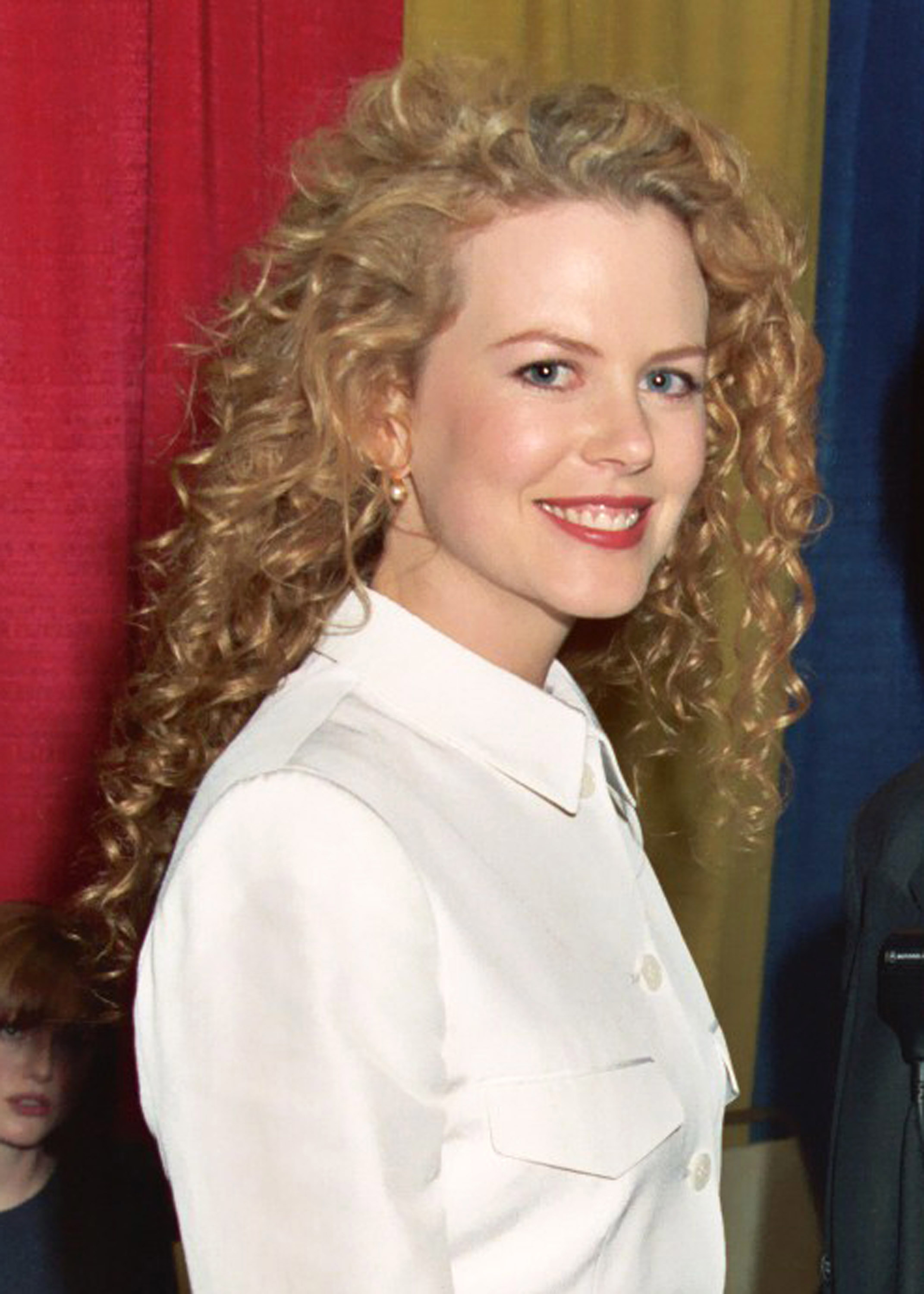 A close-up of a smiling Nicole with curly hair