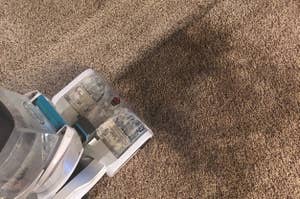Reviewer using the Hoover on their carpet and you can clearly see the clean line of the carpet next to the mess it's cleaning up