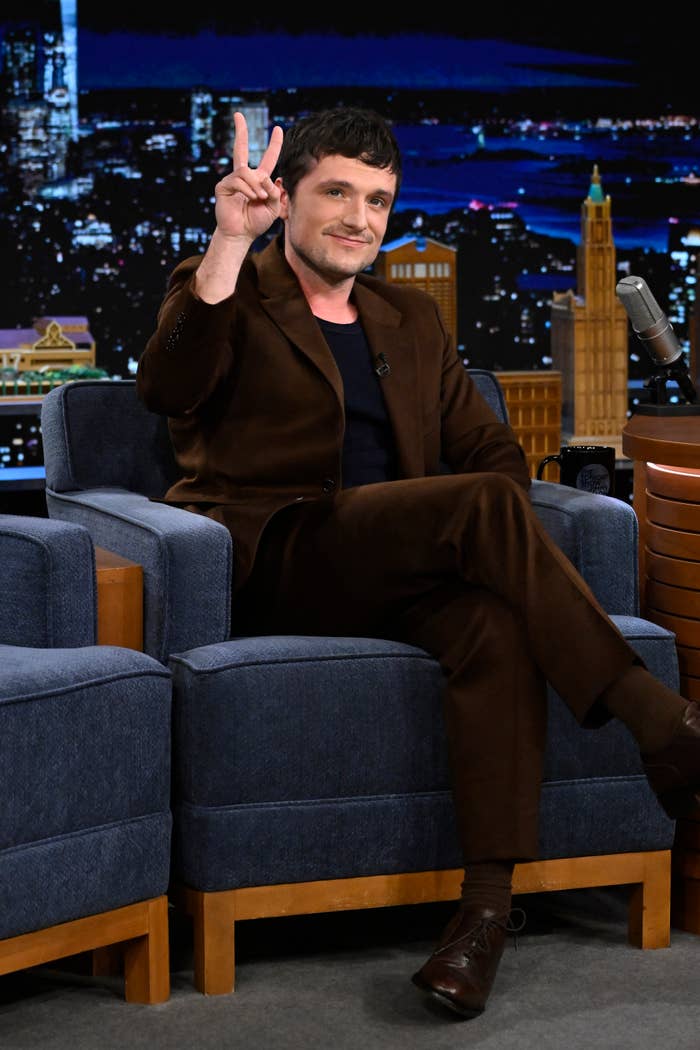 Closeup of Josh Hutcherson sitting for a late-night TV interview and giving the peace sign