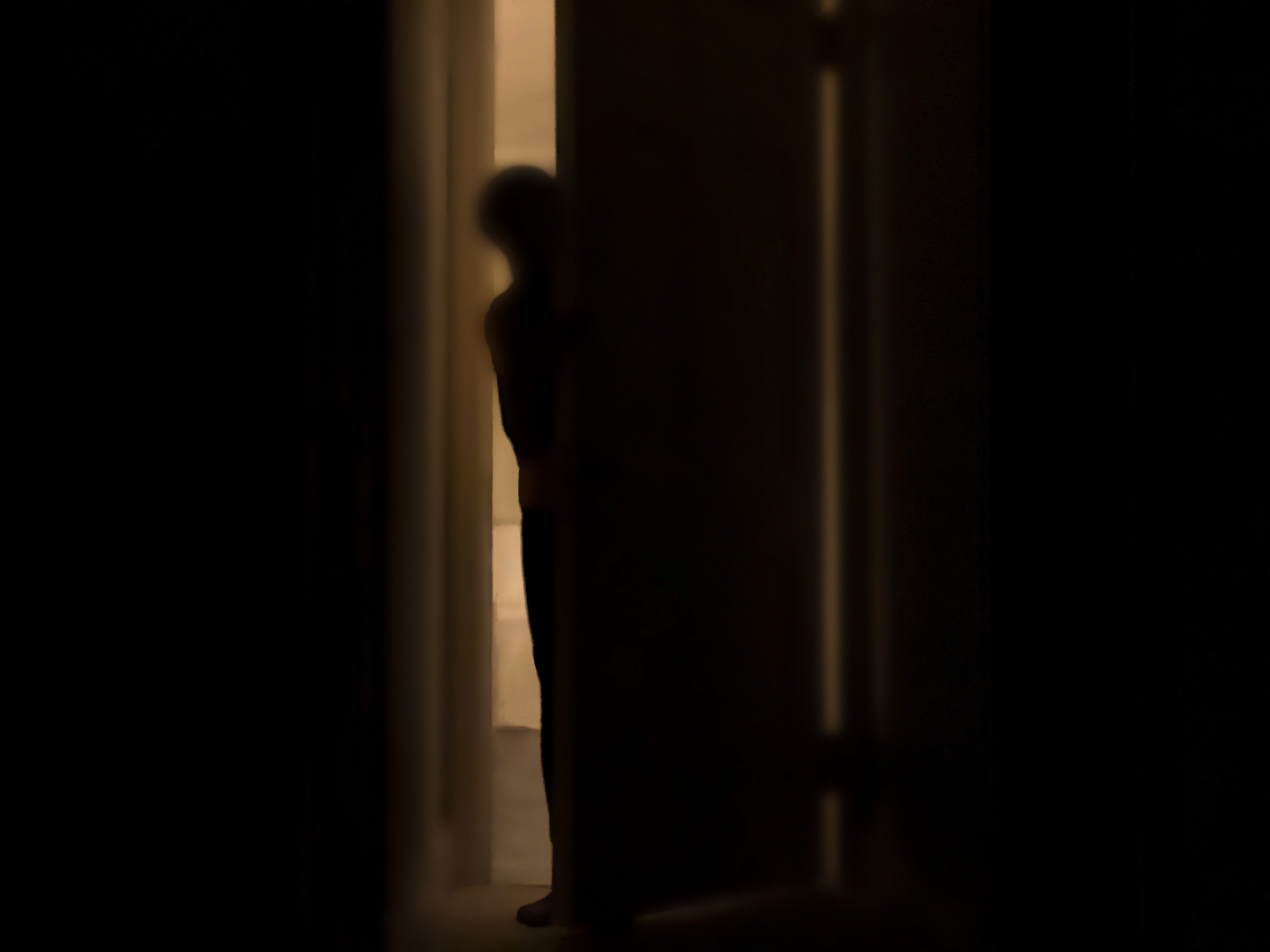 Silhouette of a person peeking into a dark room