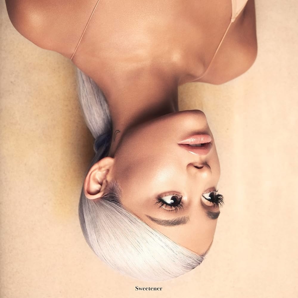 Ariana Grande lying down with head tilted back, hair swept to one side, minimal makeup. Text: Sweetener.
