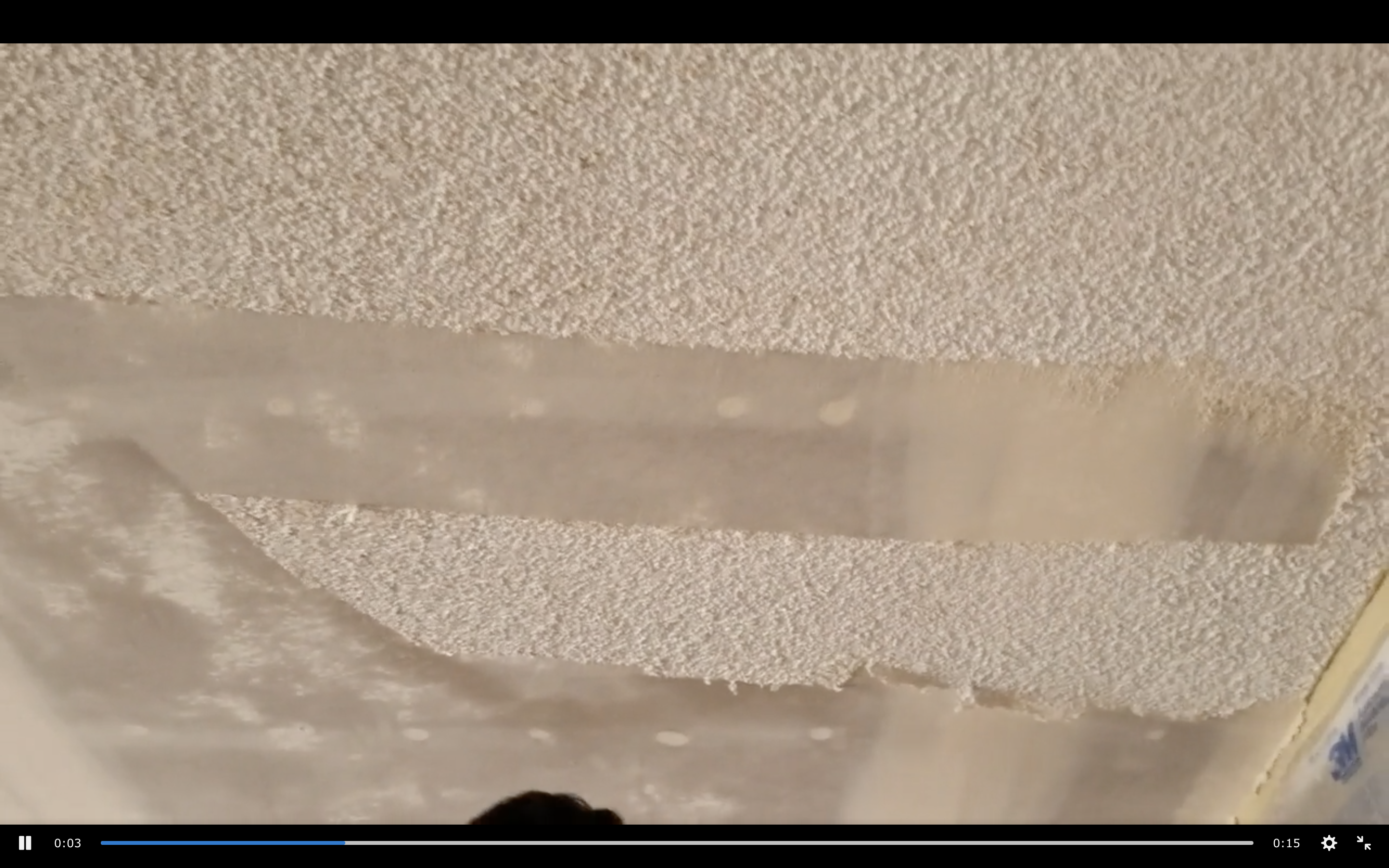 A person is scraping off their popcorn ceiling