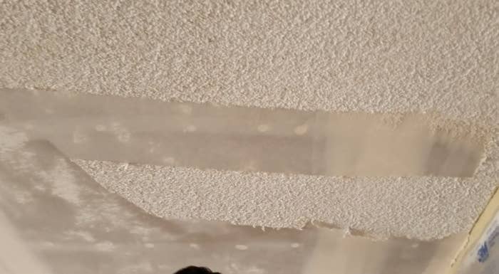 A person is scraping off their popcorn ceiling