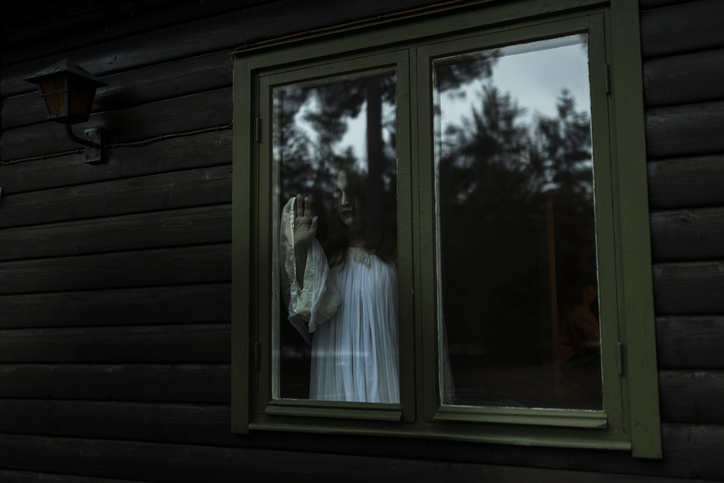 A woman wearing white and standing by a window