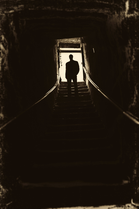 A dark shadow man at the top of a flight of stairs