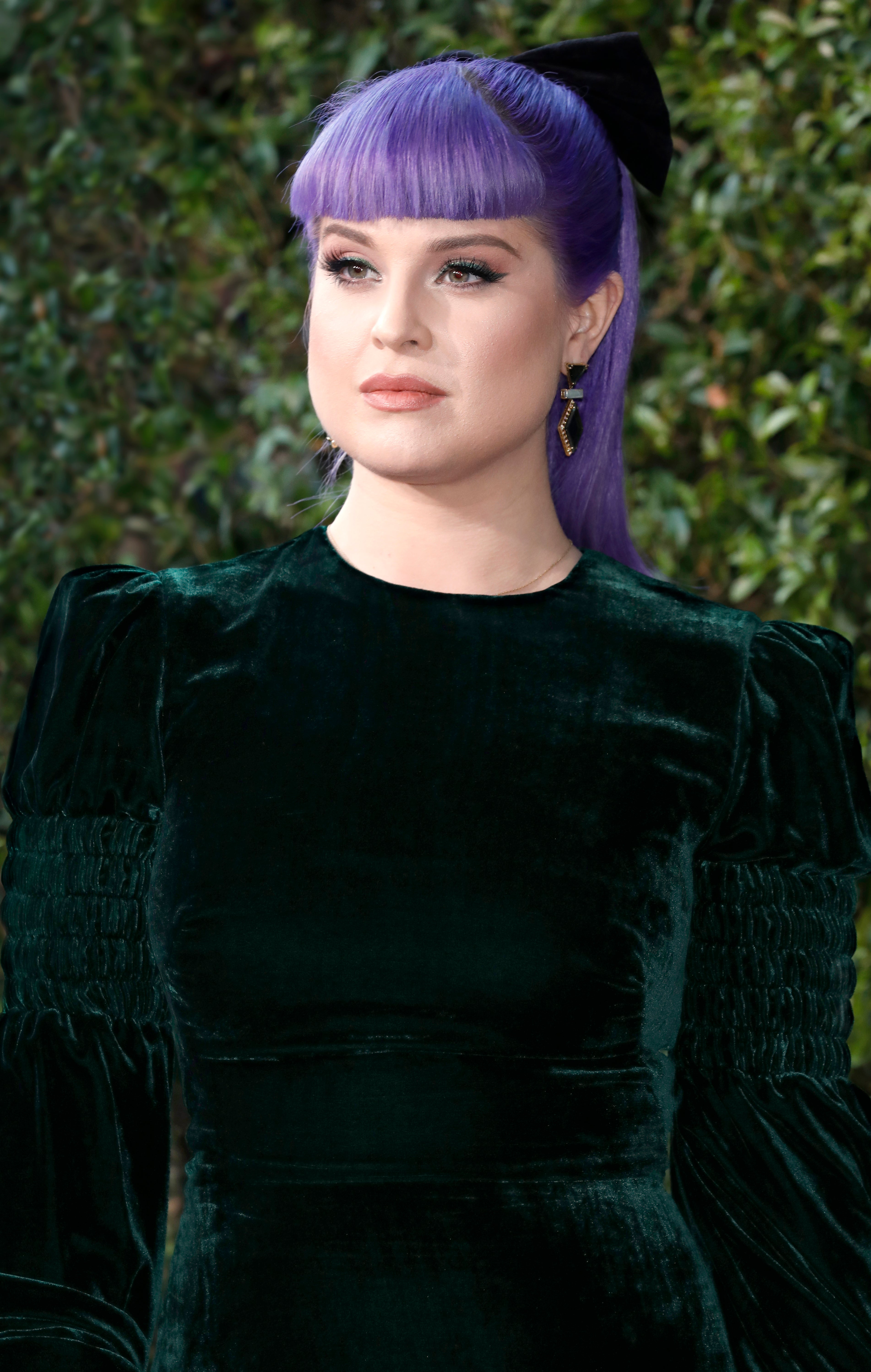 Close-up of Kelly at a media event in a long-sleeved velvet outfit