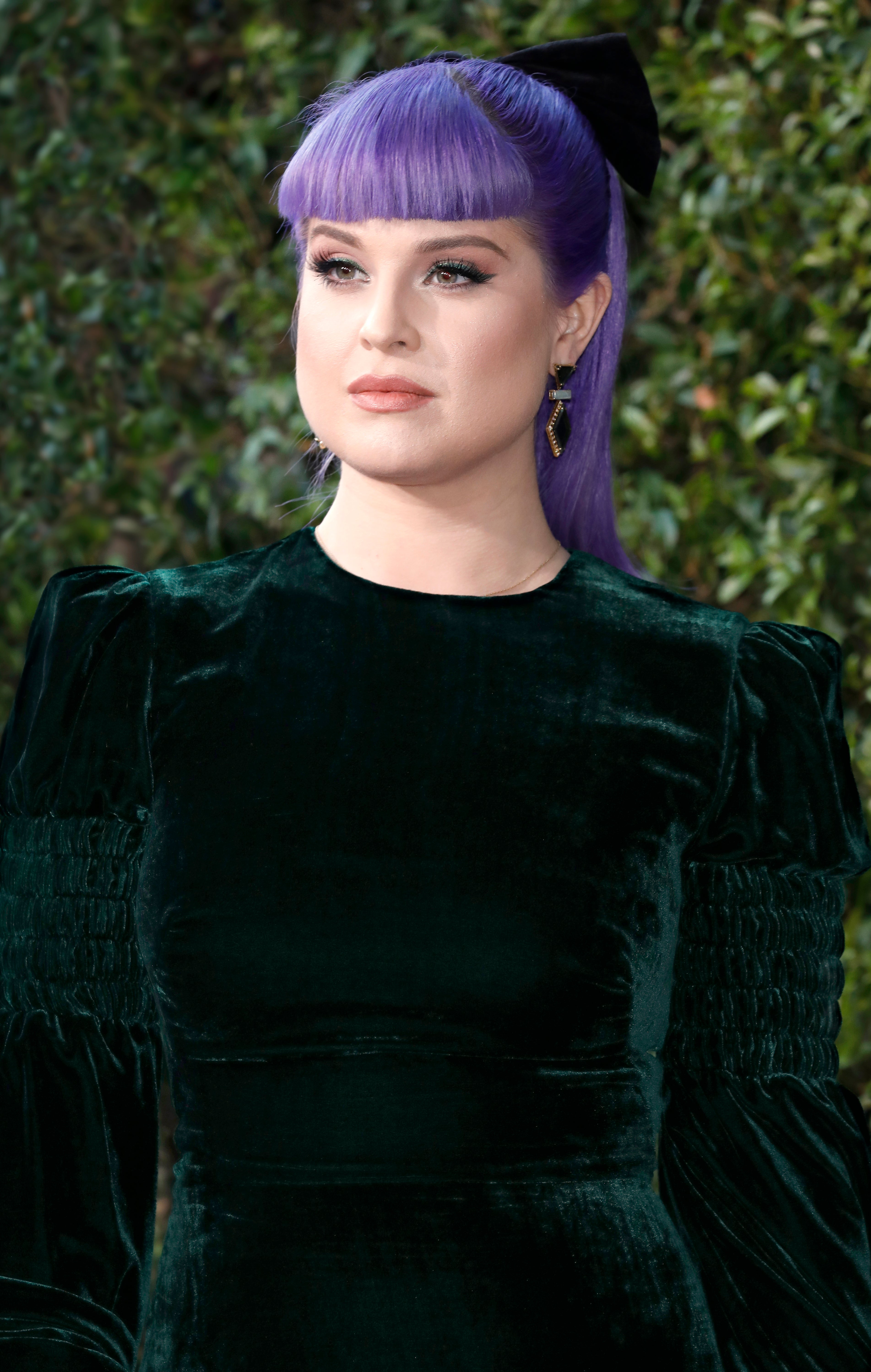 Close-up of Kelly at a media event in a long-sleeved velvet outfit