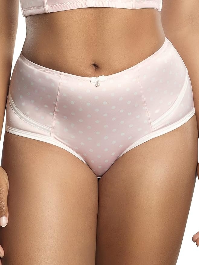 model wearing high-rise pink retro-style brief undies with polka-dot pattern