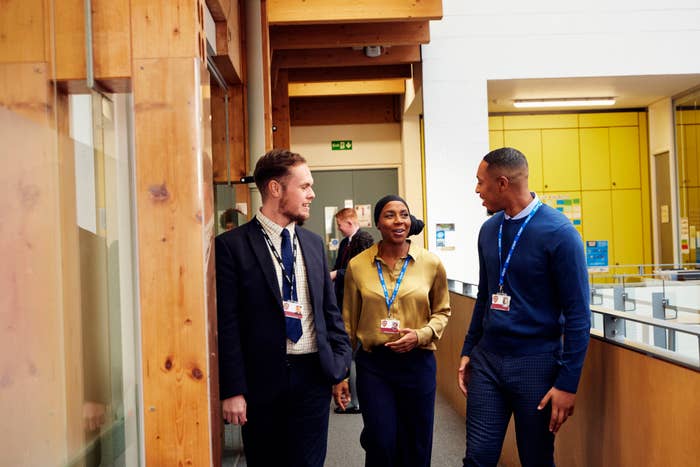 Three teachers in a hallway having a conversation