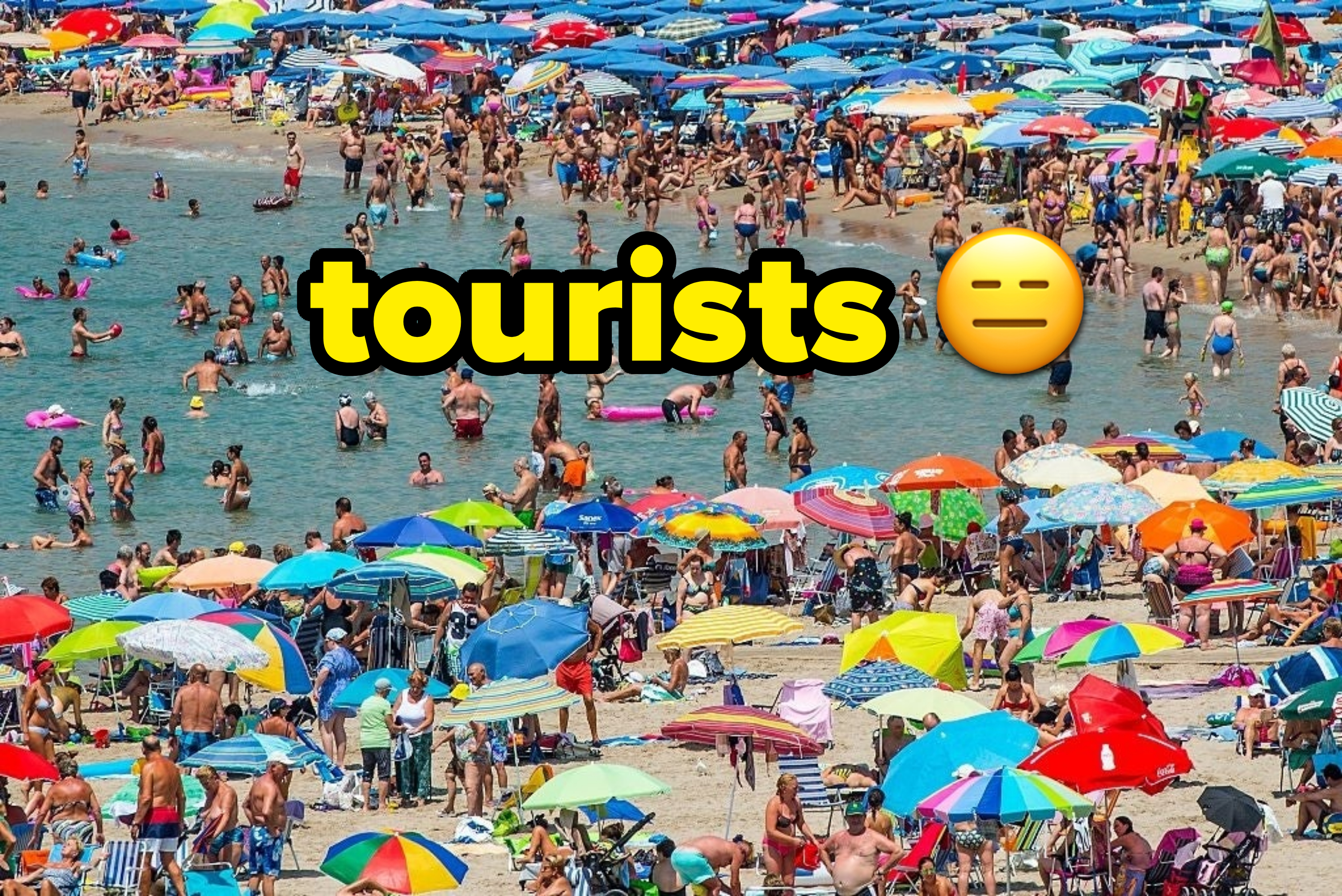 crowded beach with the word tourists
