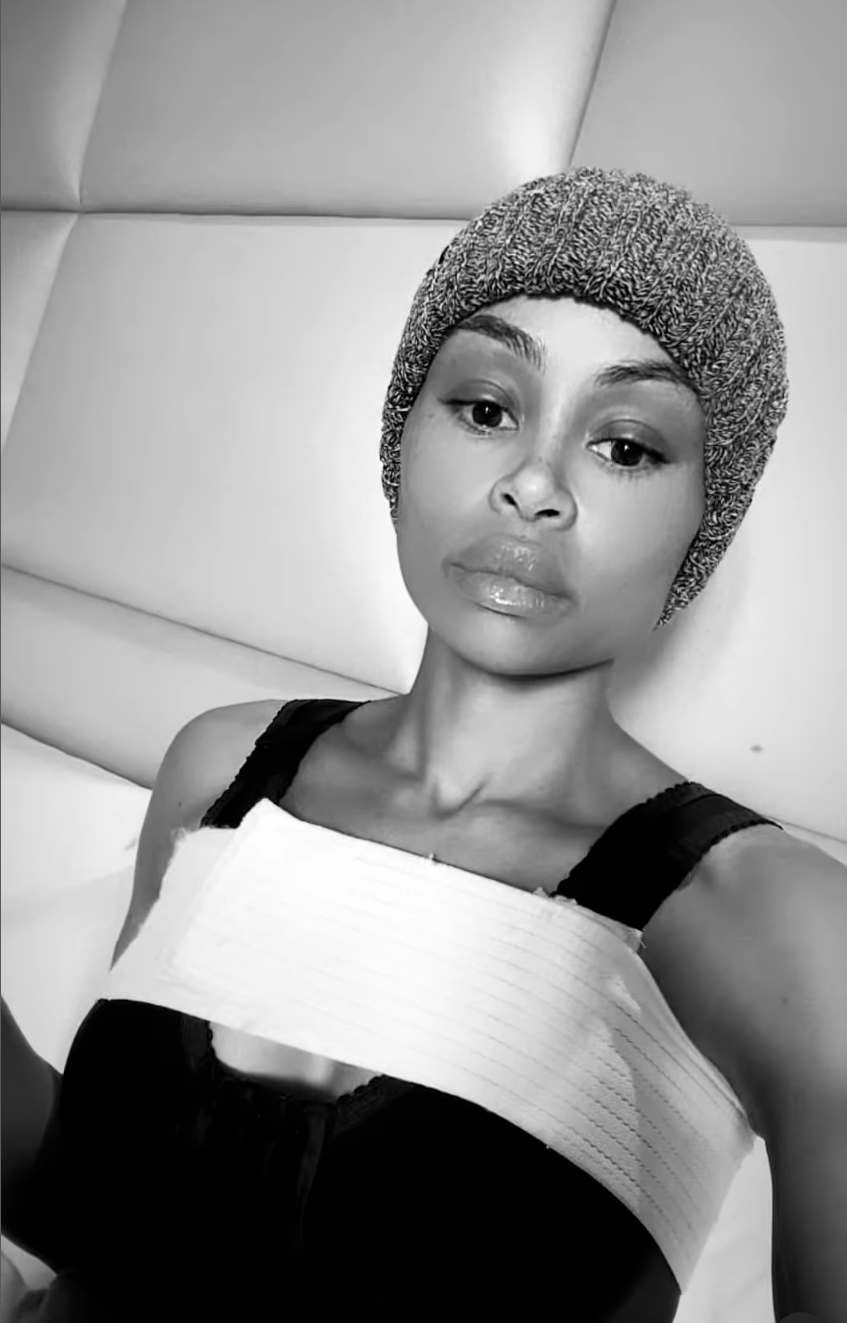 black and white selfie with her hair in a beanie and a wrap across her chest