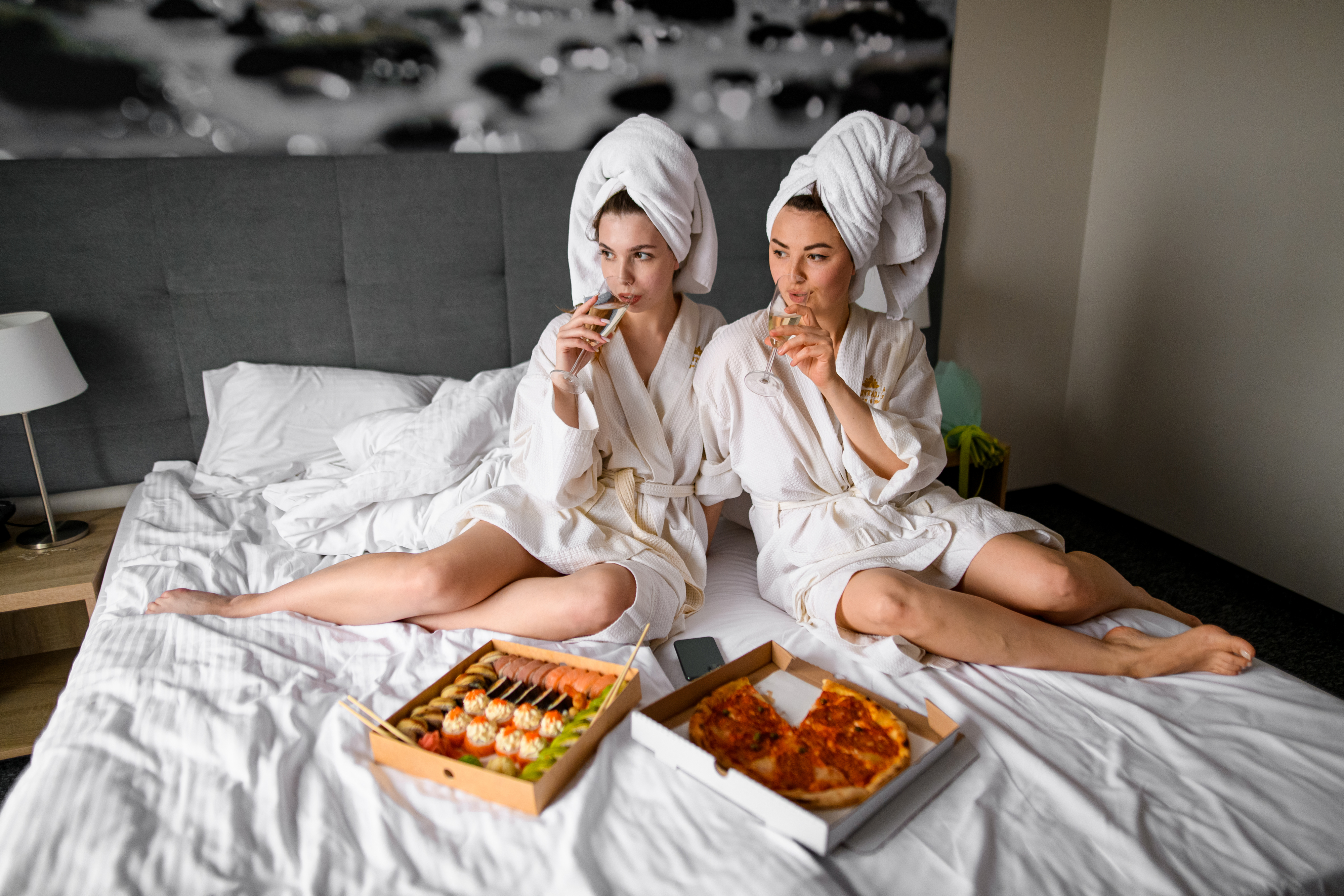 two friends with pizza and sushi in their robes relaxing