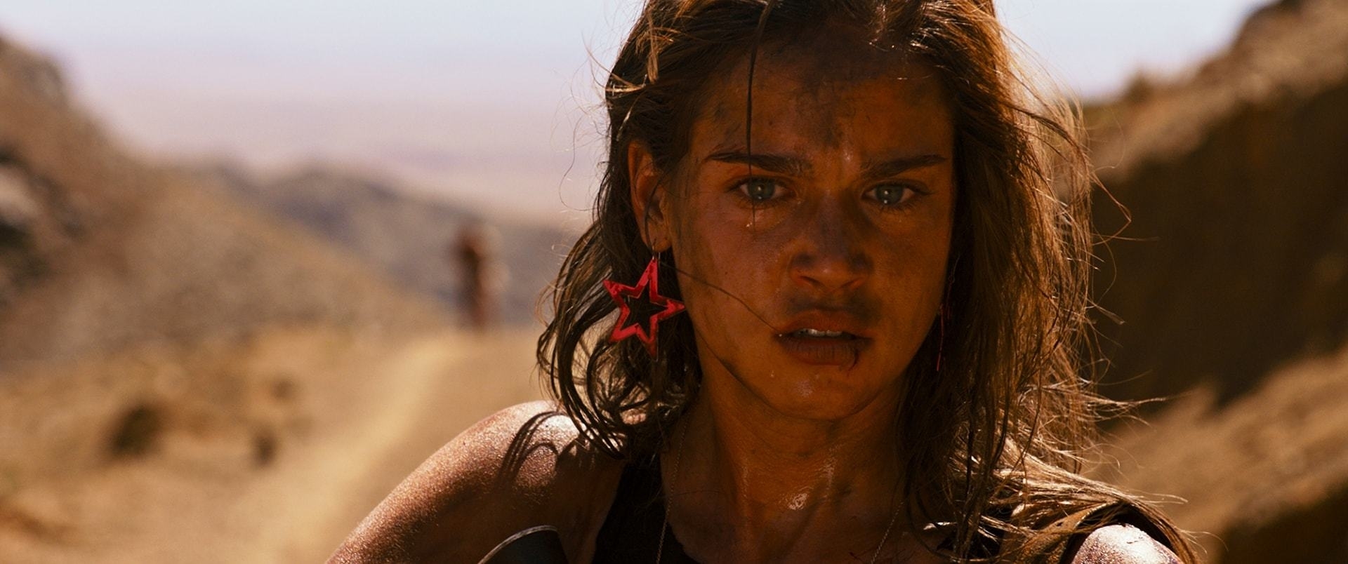 Matilda Lutz wearing pink star-shaped earrings in the desert.