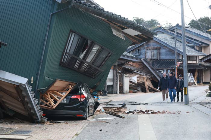 People walking by buildings collapsed from the earthquake