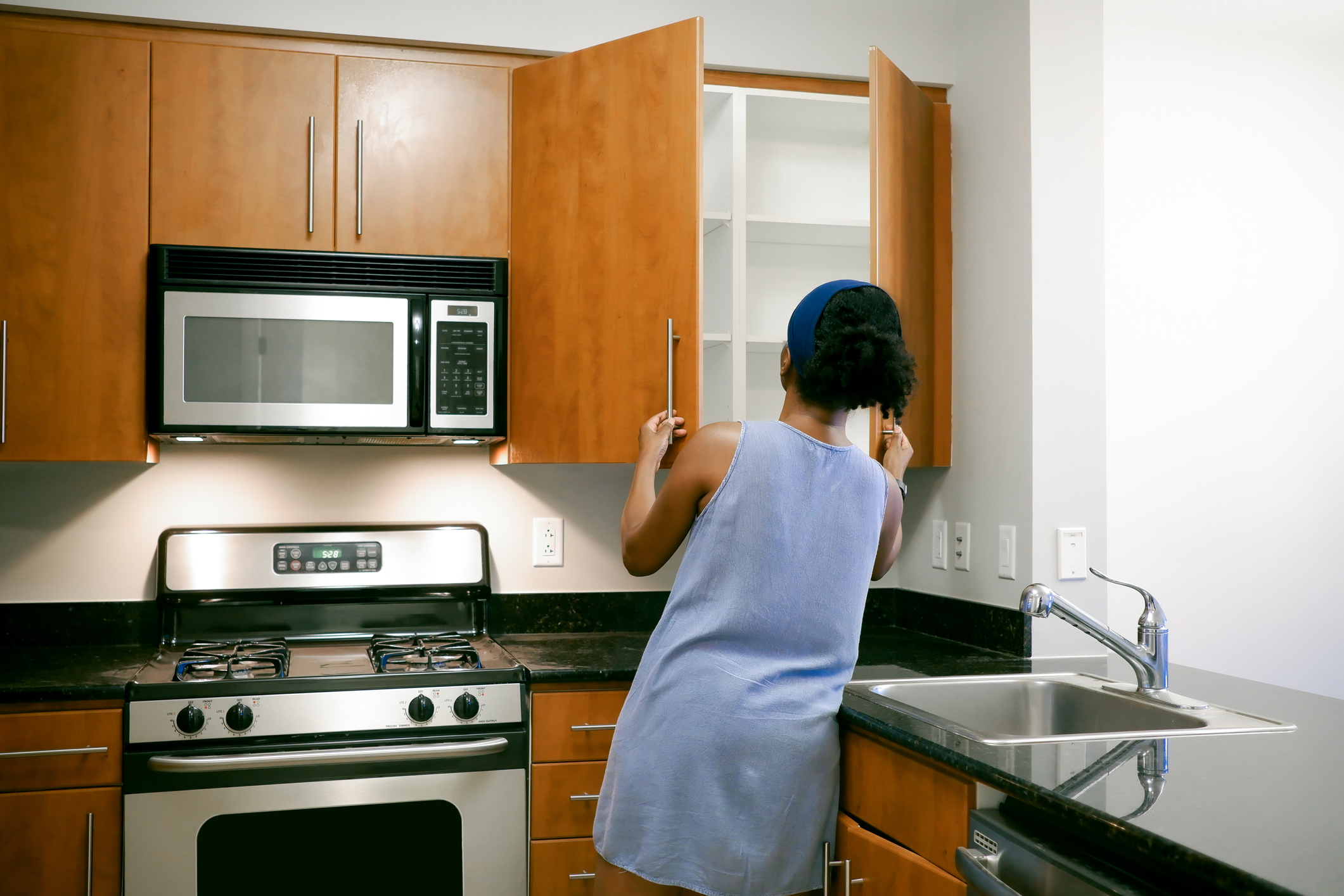 A woman looking through kitchen cabinets