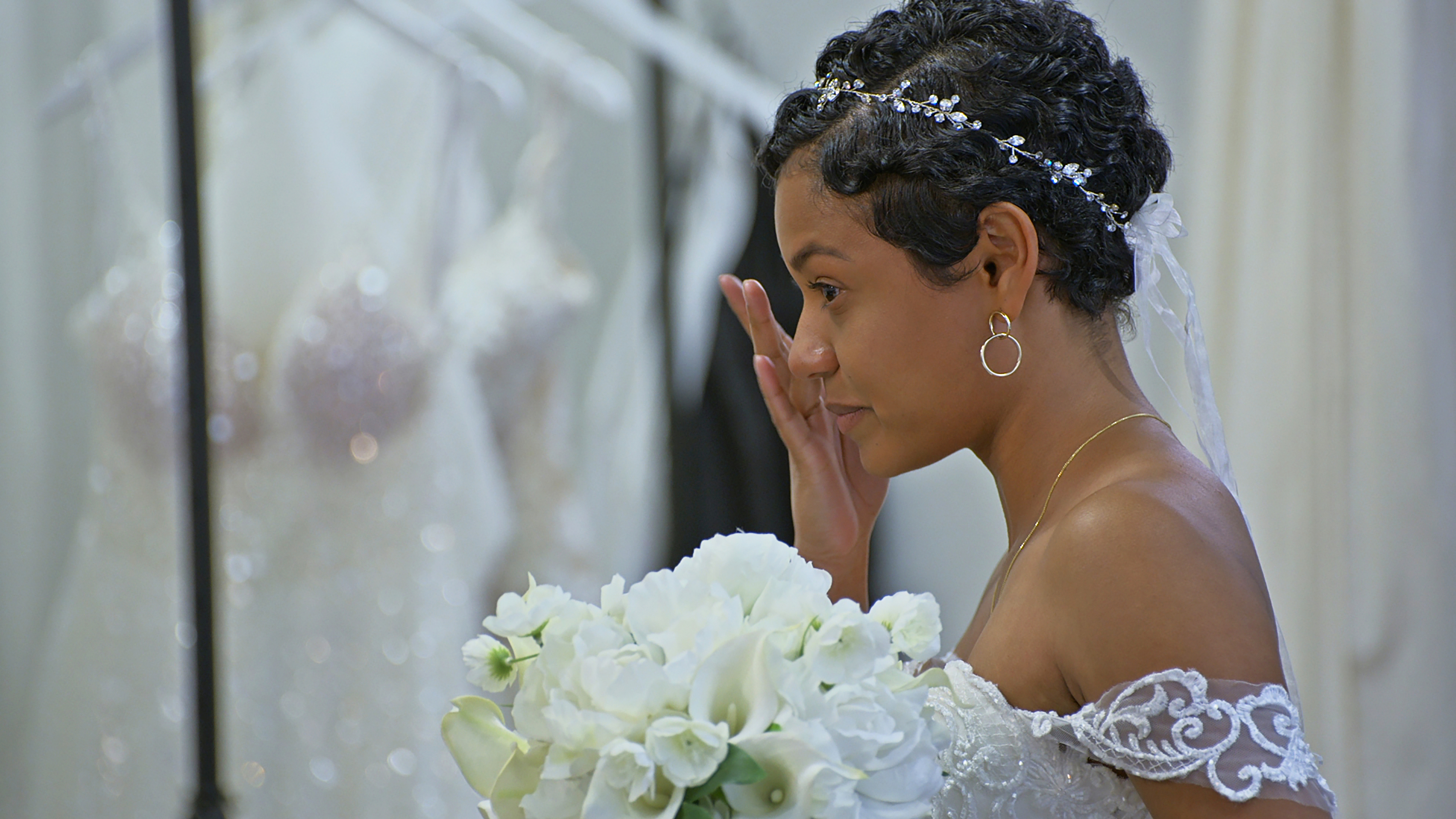 Iyanna wiping away tears while she wears her wedding dress inside a bridal store