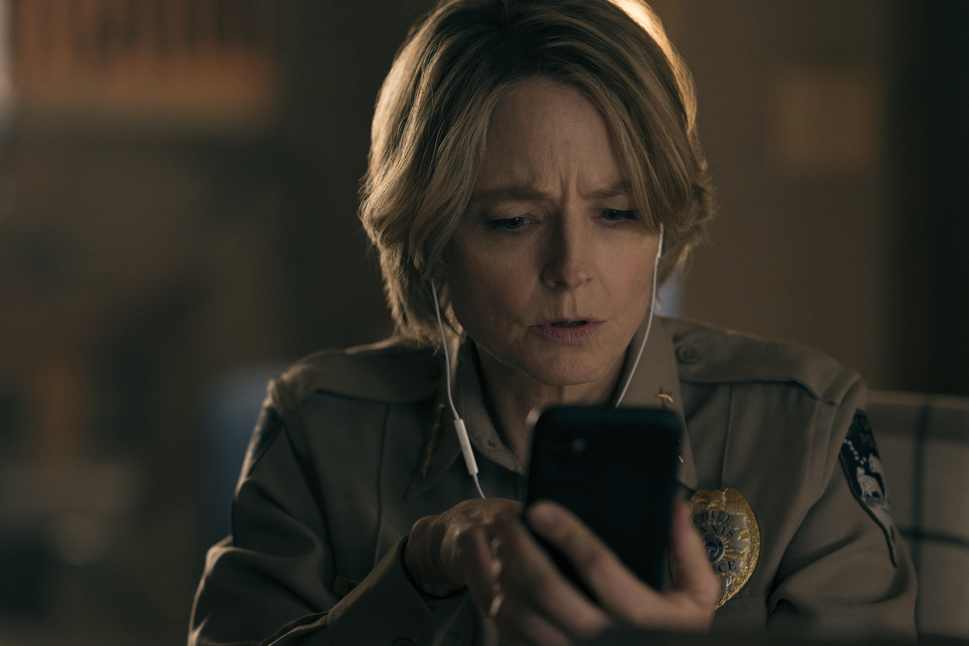 Jodie watching something on a phone with headphones in her ears in a scene from &quot;True Detective&quot;