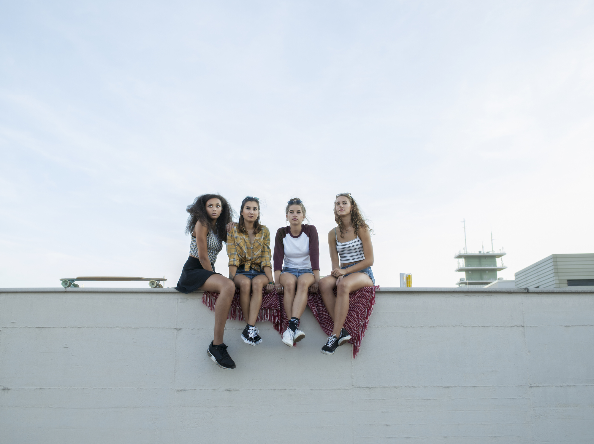 A group of teen girls are sitting on a wall