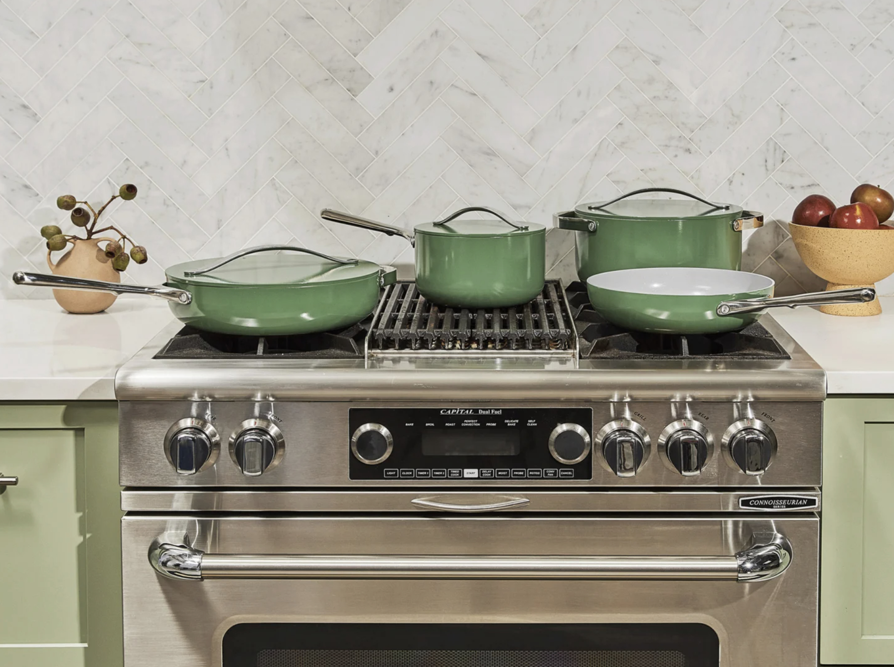 The cookware set in sage on a stovetop