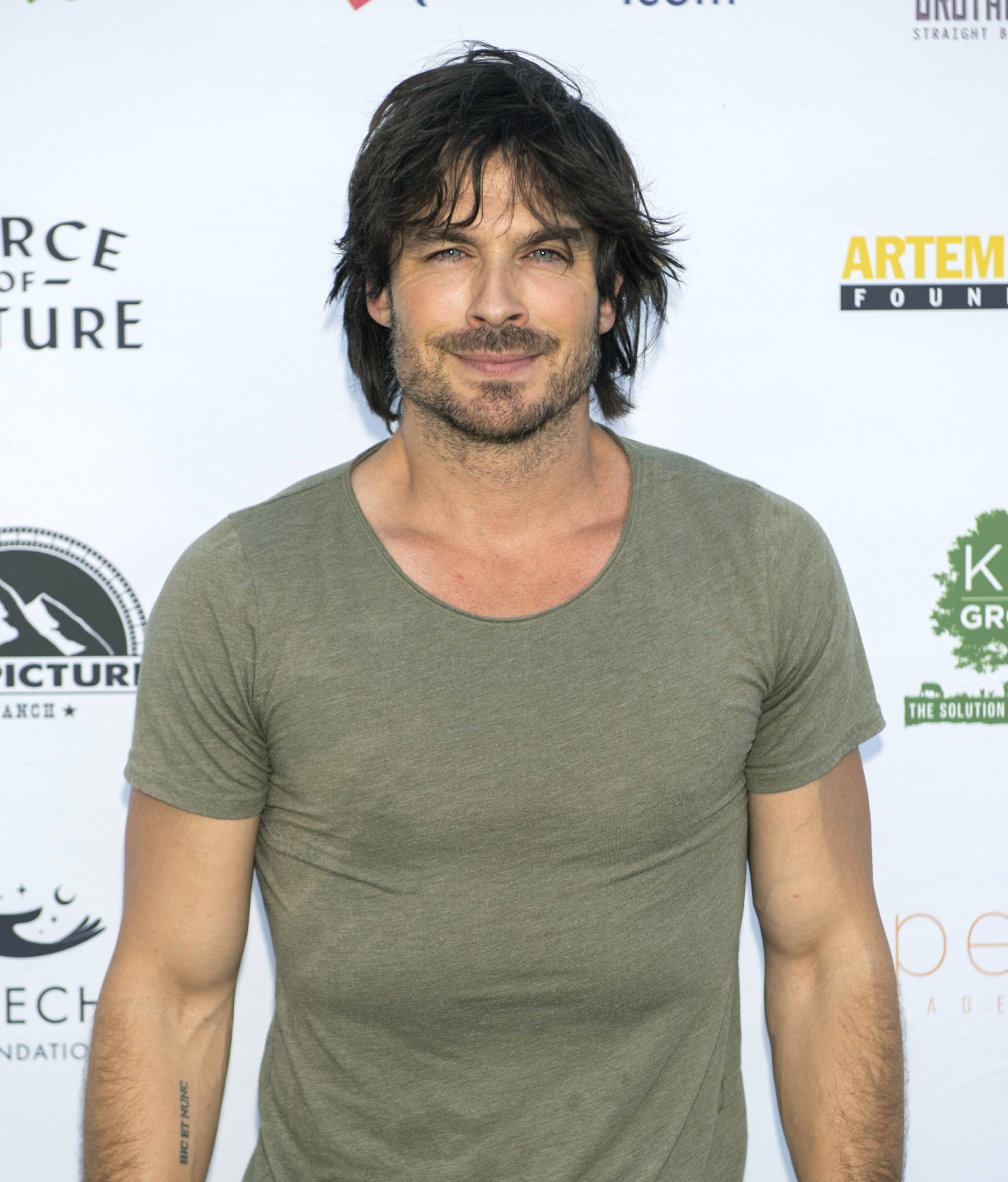 Close-up of Ian at a media event wearing a short-sleeved T-shirt