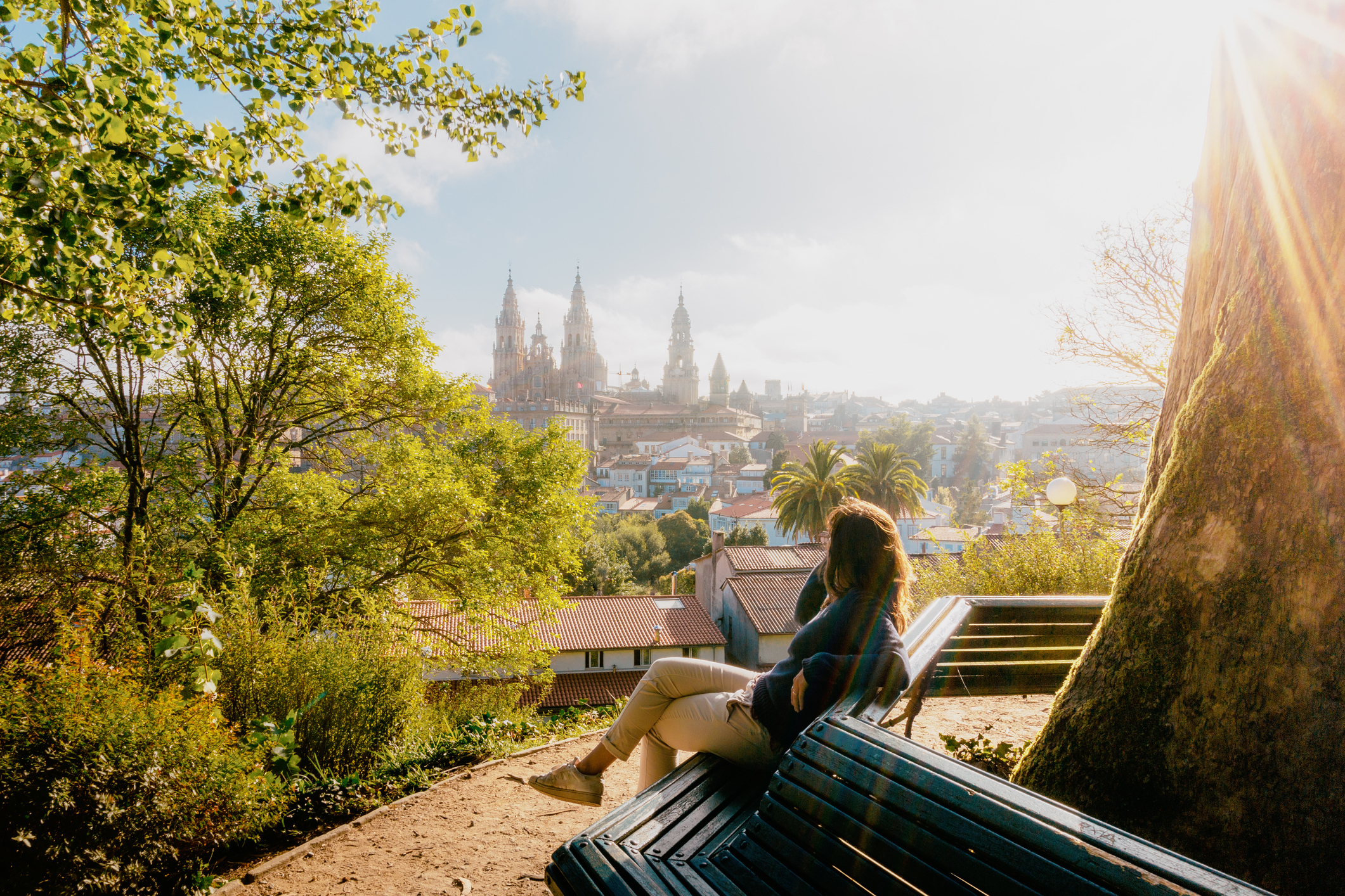 A woman sitting on a bench overlooking a beautiful city