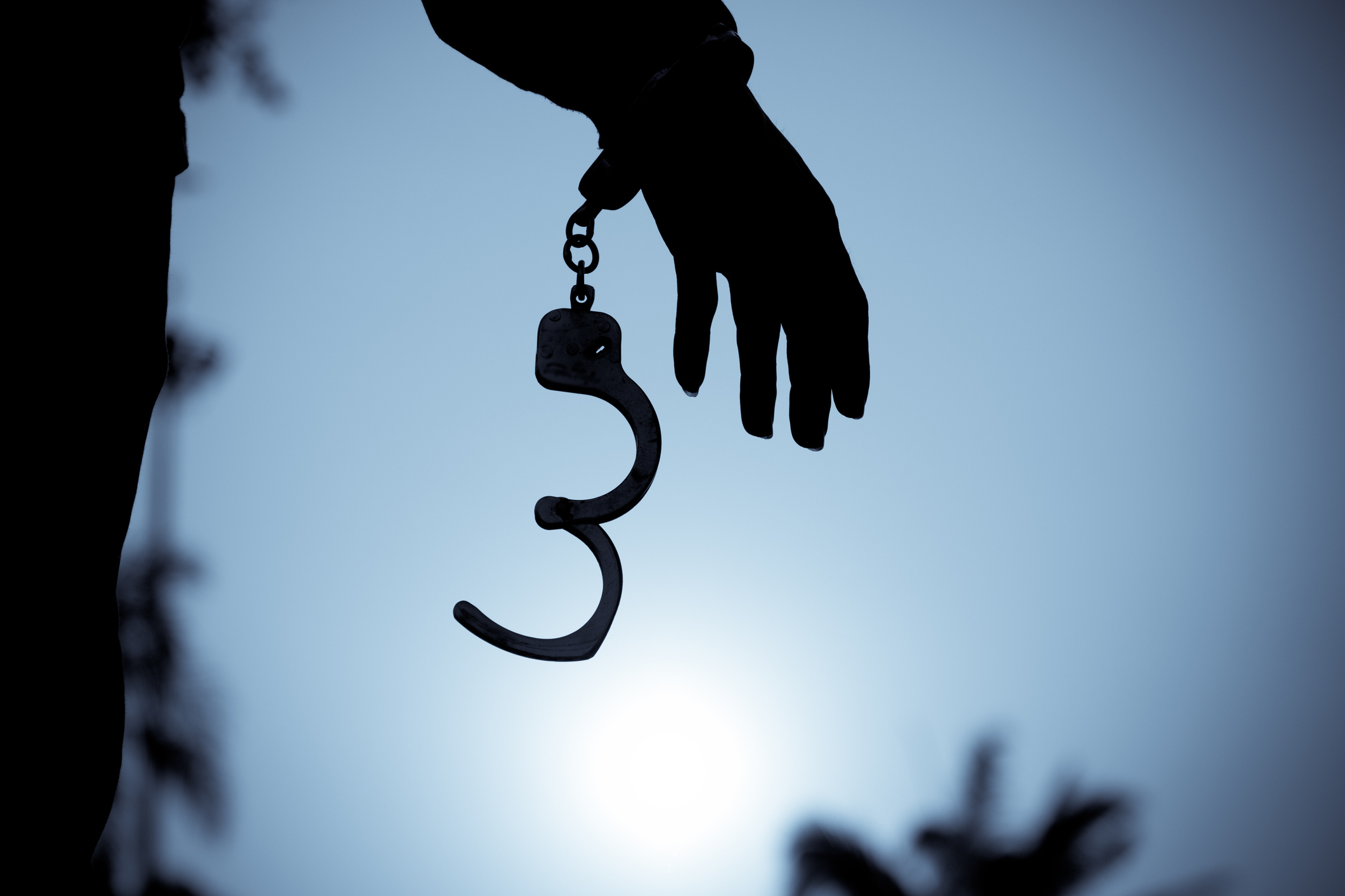 A hand with handcuffs hanging from it