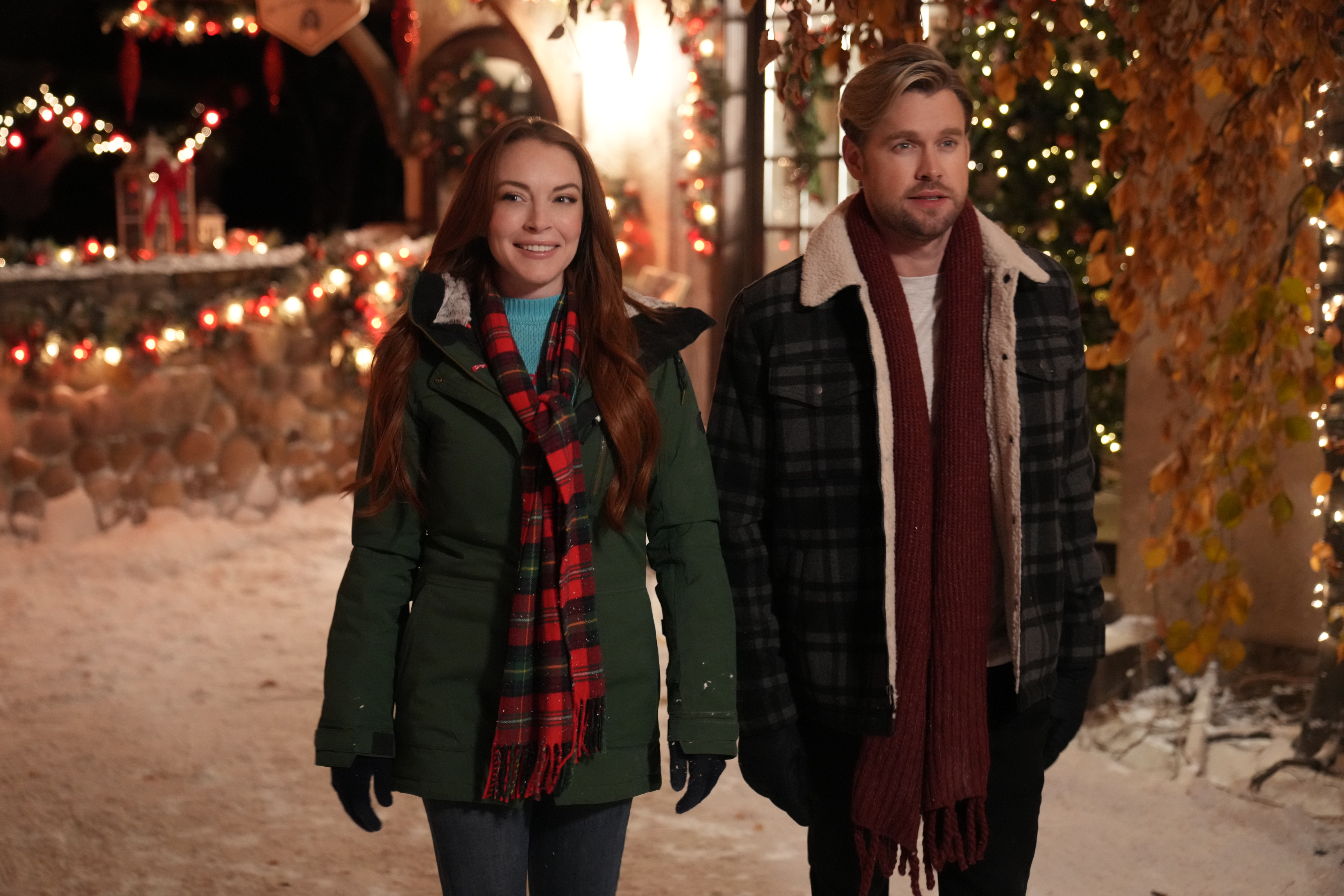Lindsay and Chord walking through a snow-y decorated town in a scene from &quot;Falling for Christmas&quot;