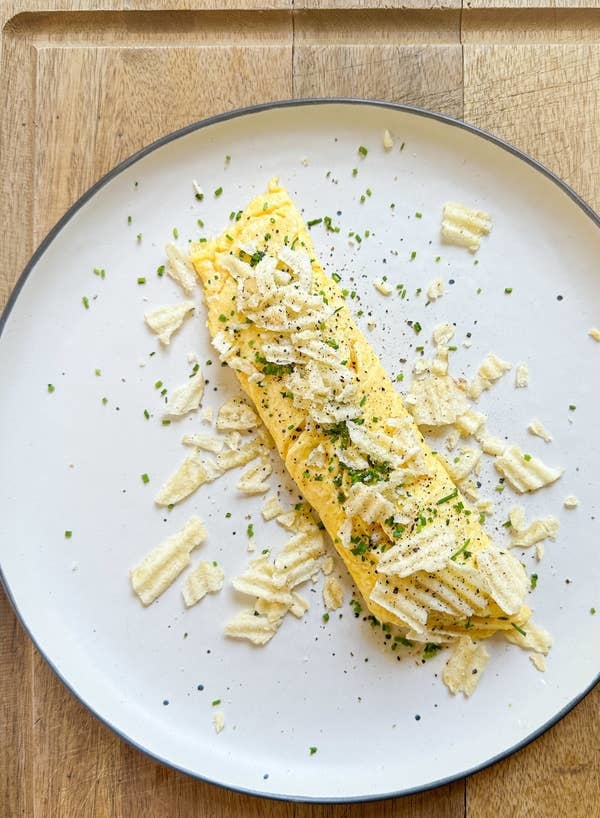 Omelet topped with chives and potato chips on a plate