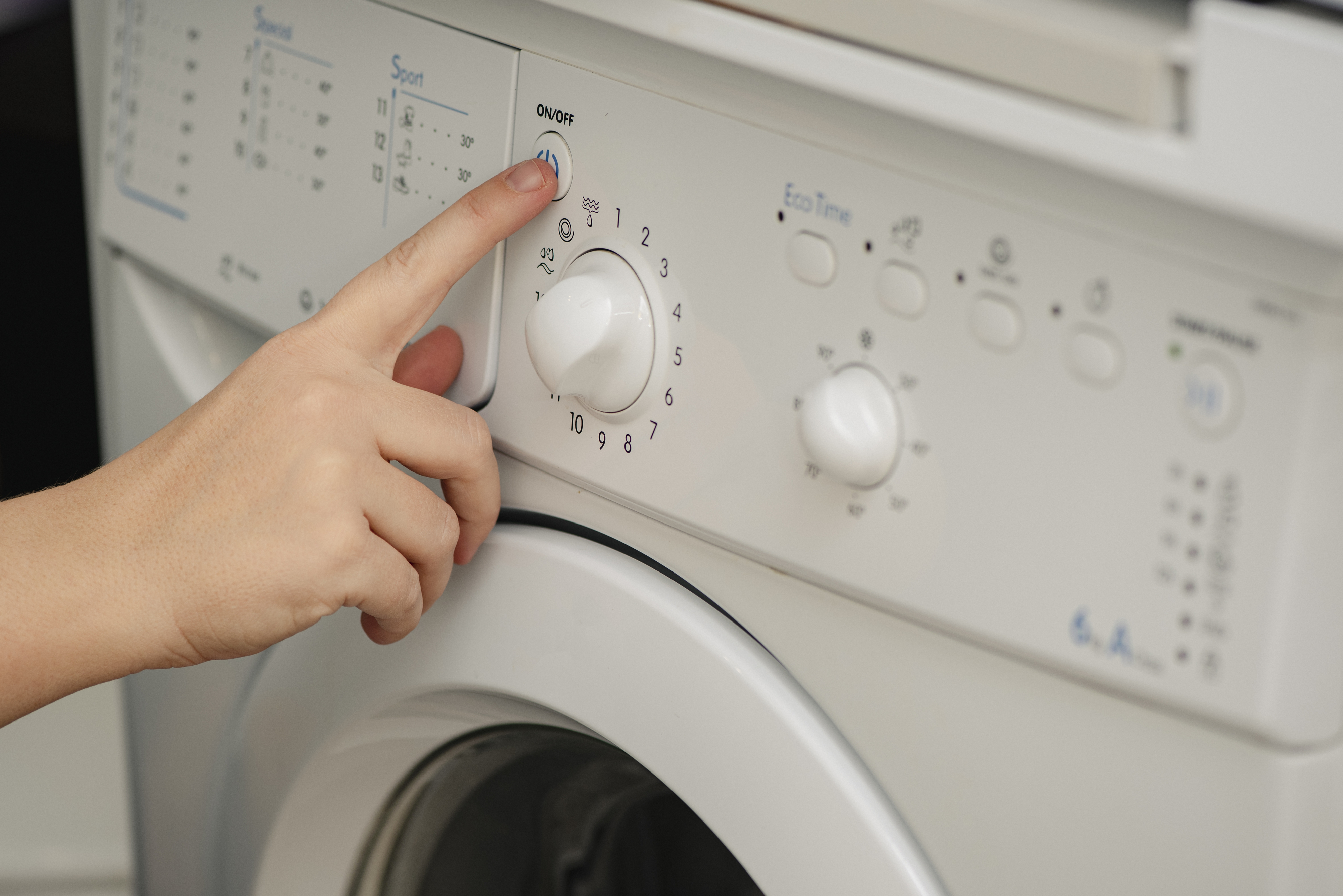 Hand Of Person Adjusting Washing Machine Knob