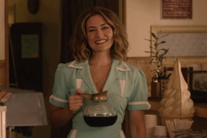 server holding a pot of coffee and smiling