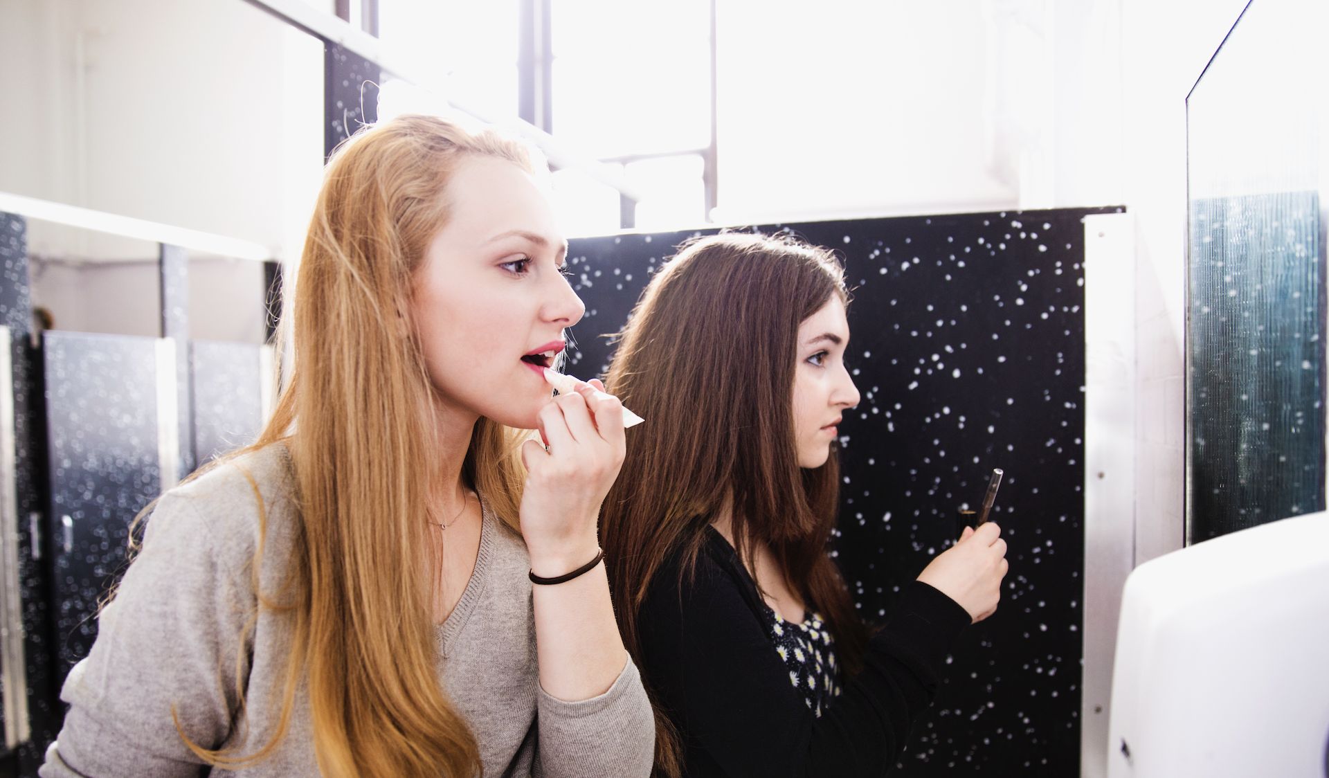Teenage girls applying makeup in a bathroom