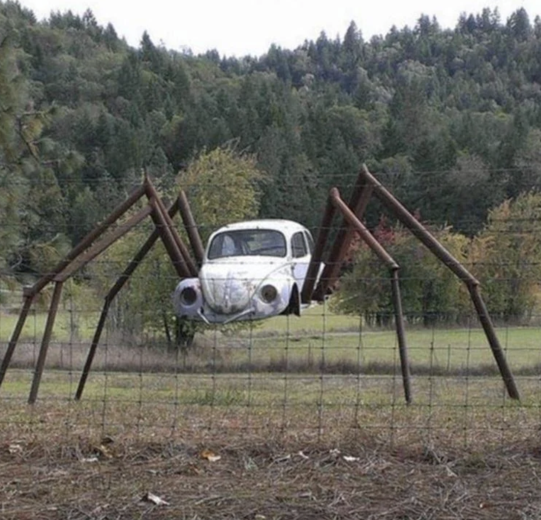the shell of a beatle volkswagon car is made into the body of a large metal spider installation