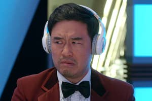 Randall Park wearing headphones and a suit.