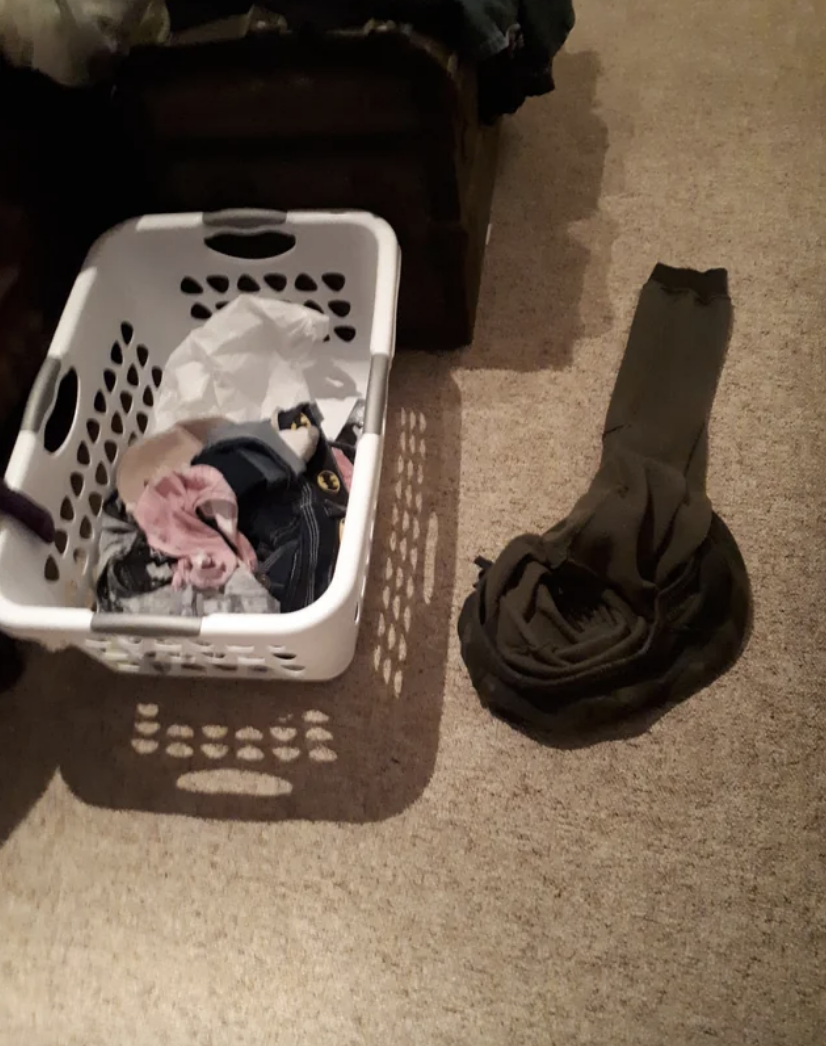 clothes on the floor next to a laundry basket