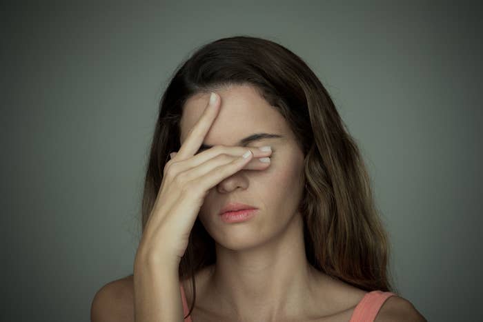 A woman covering her eyes with her hand