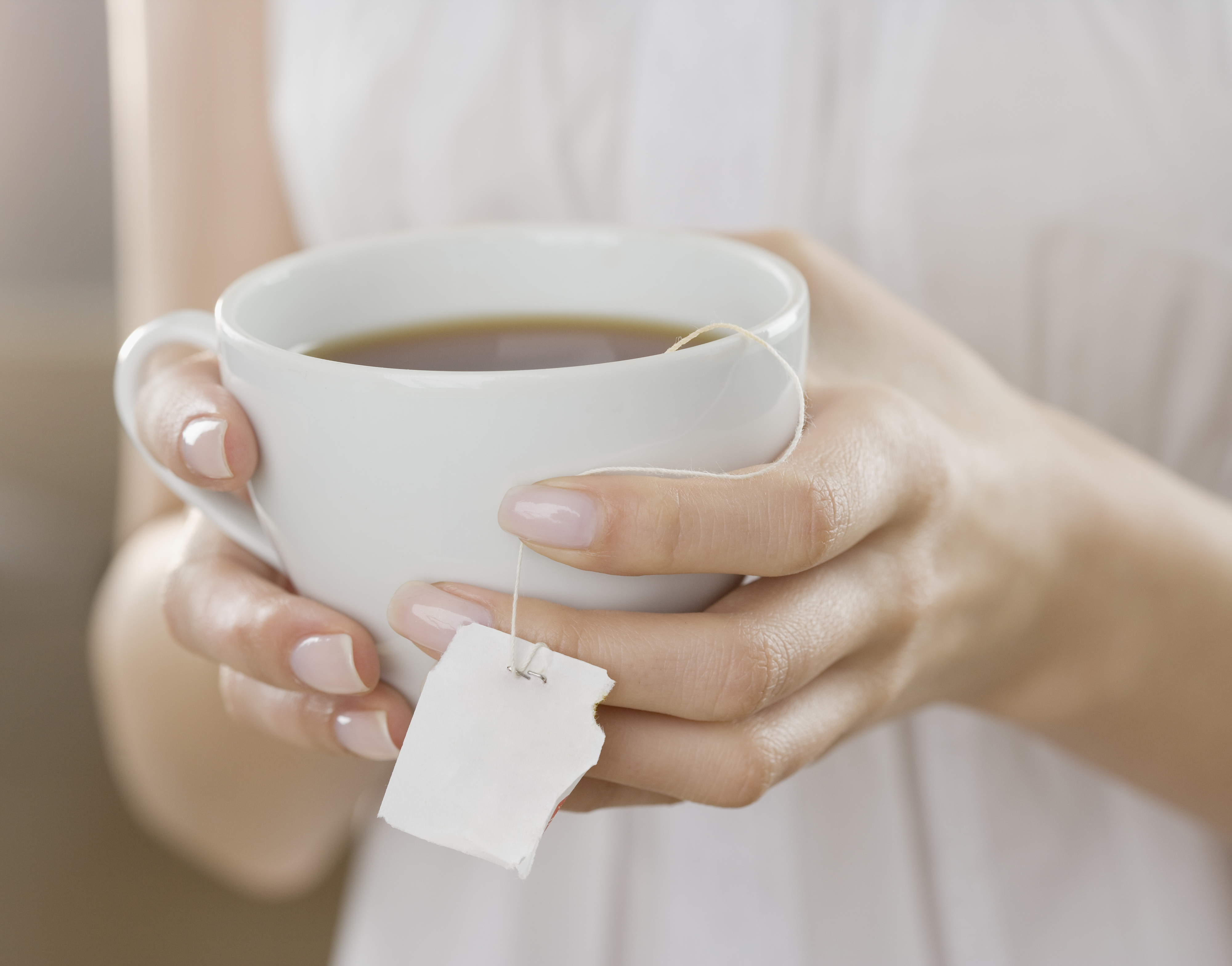 A person holding a cup of tea with a tea bag