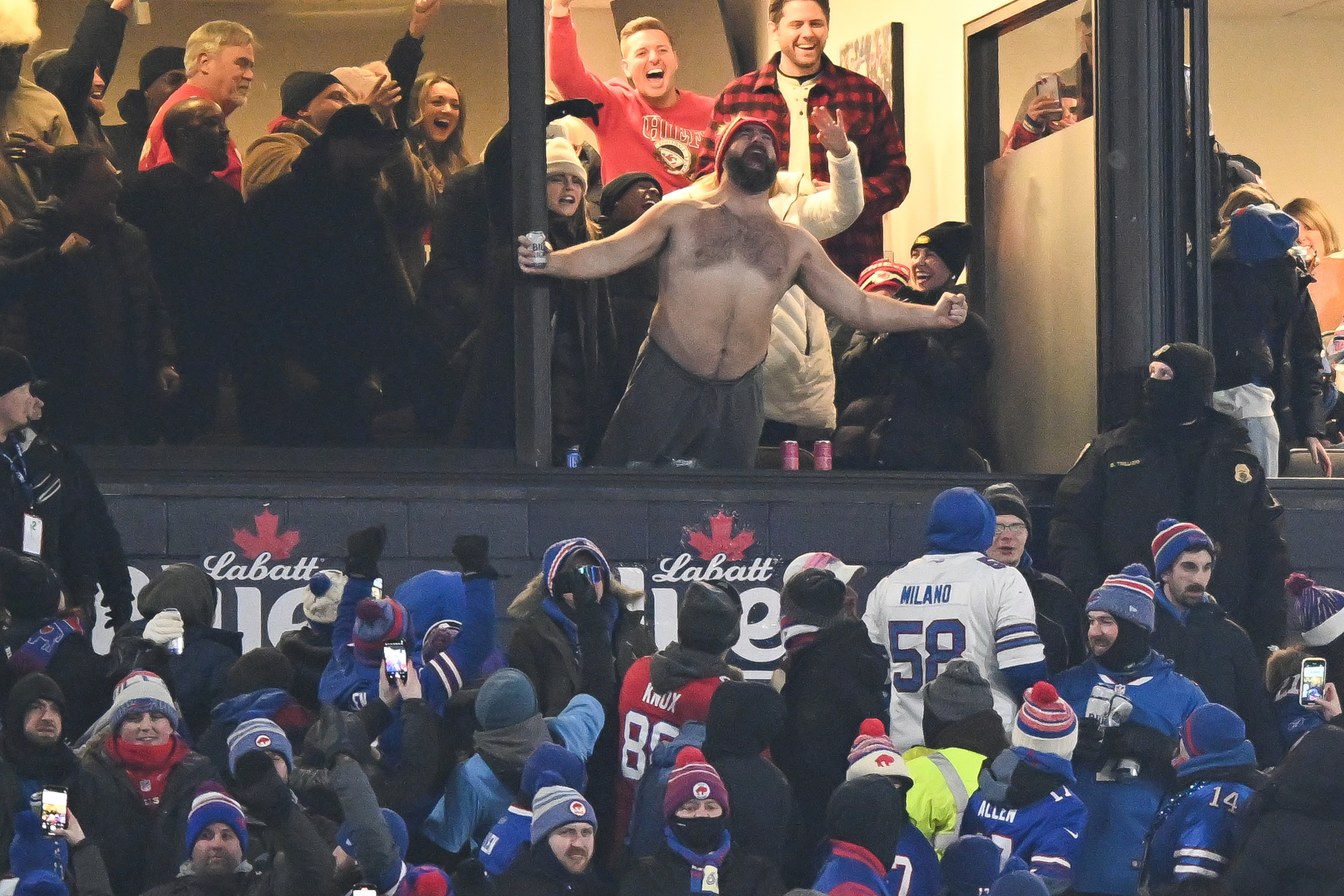jason leaning shirtless out of the window with Bills fans below him