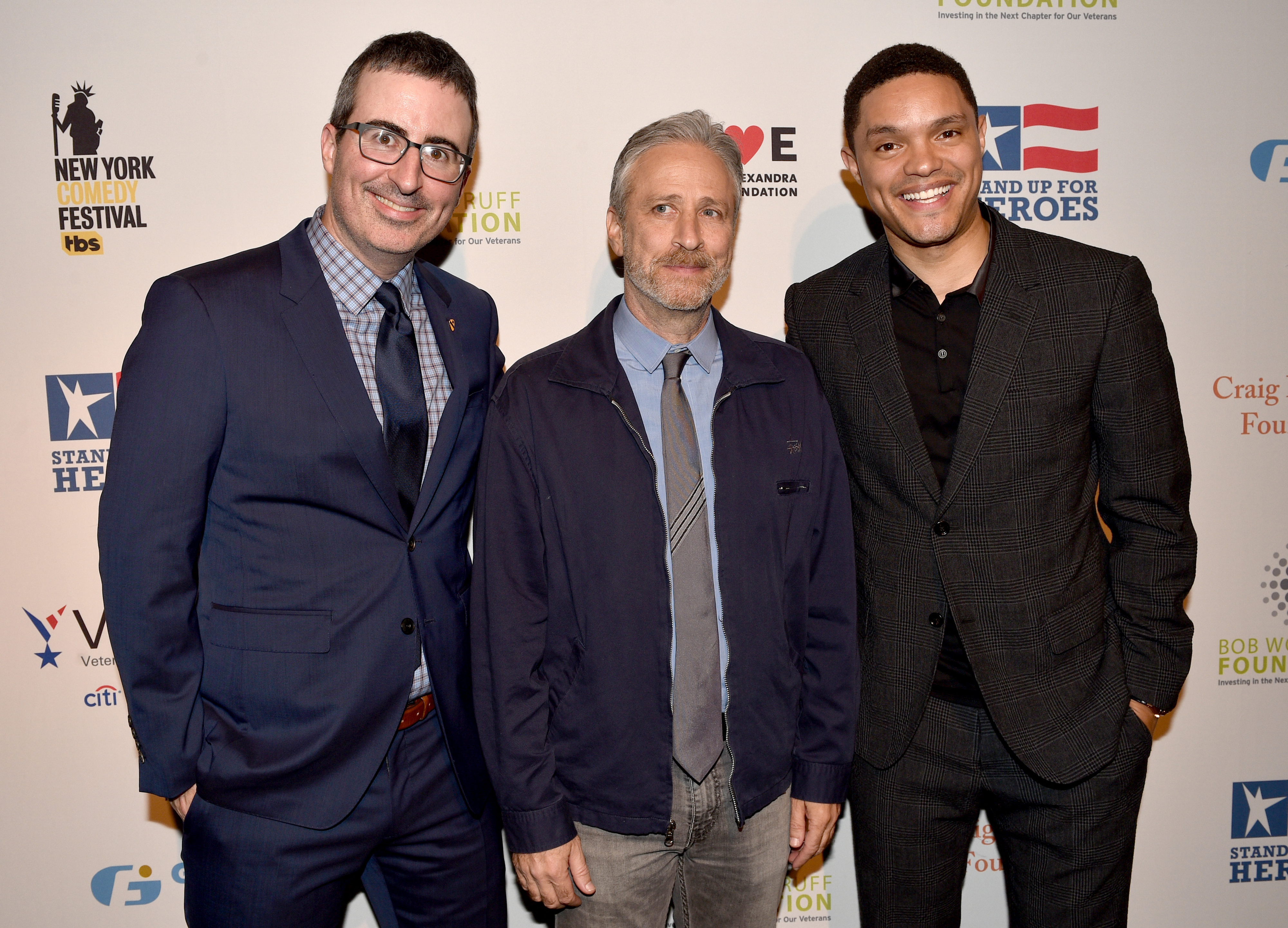 Jon Stewart standing between Trevor Noah and John Oliver