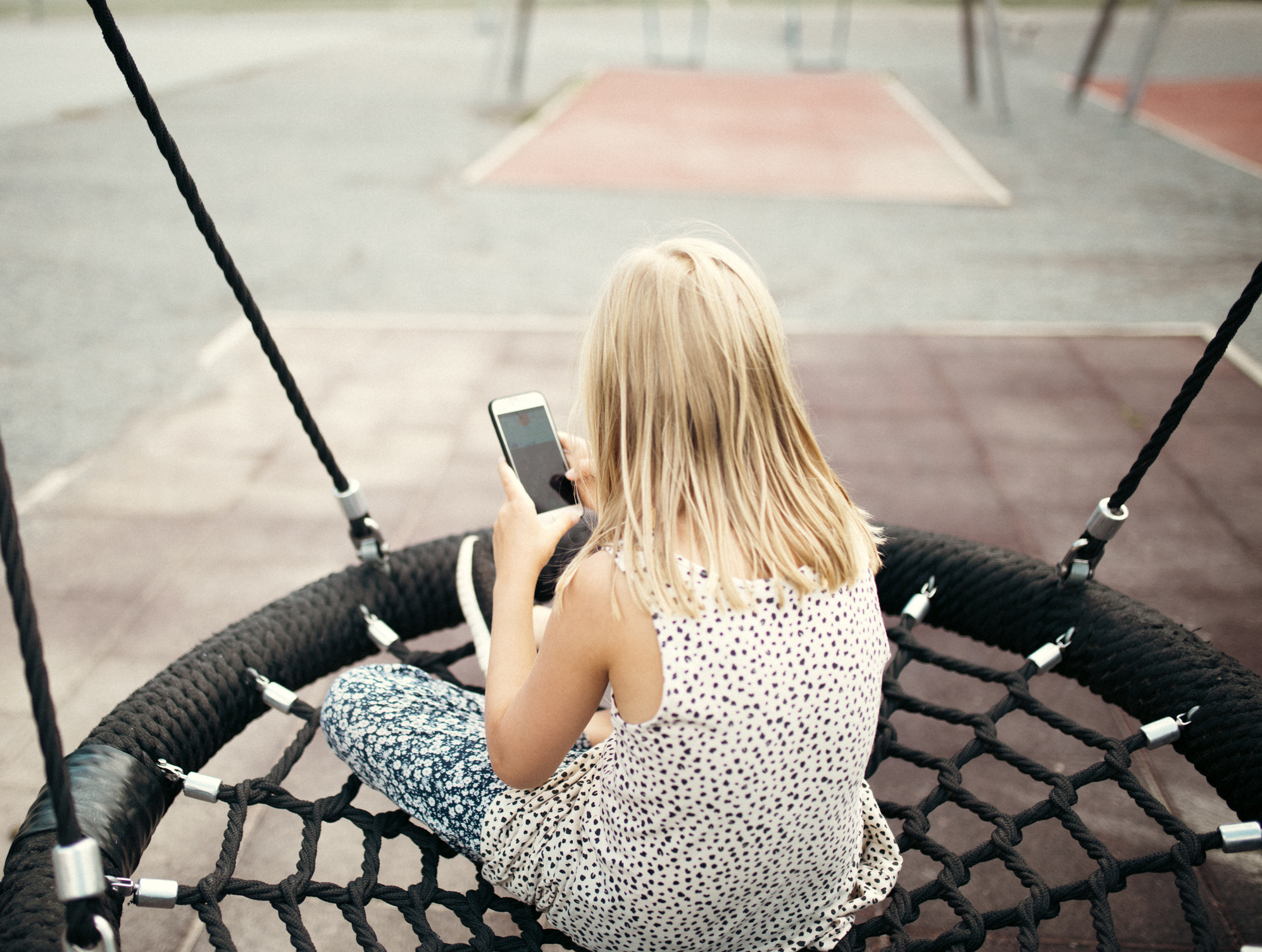 Photo of a young girl looking at her phone on the playground