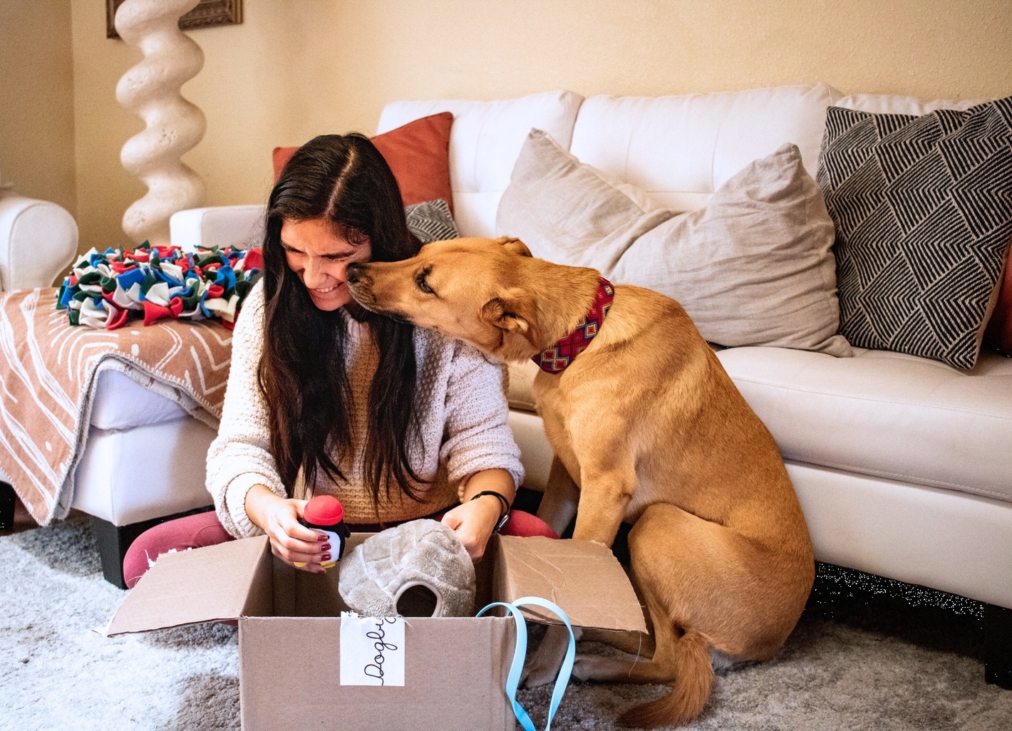 A model opening up the box with their dog